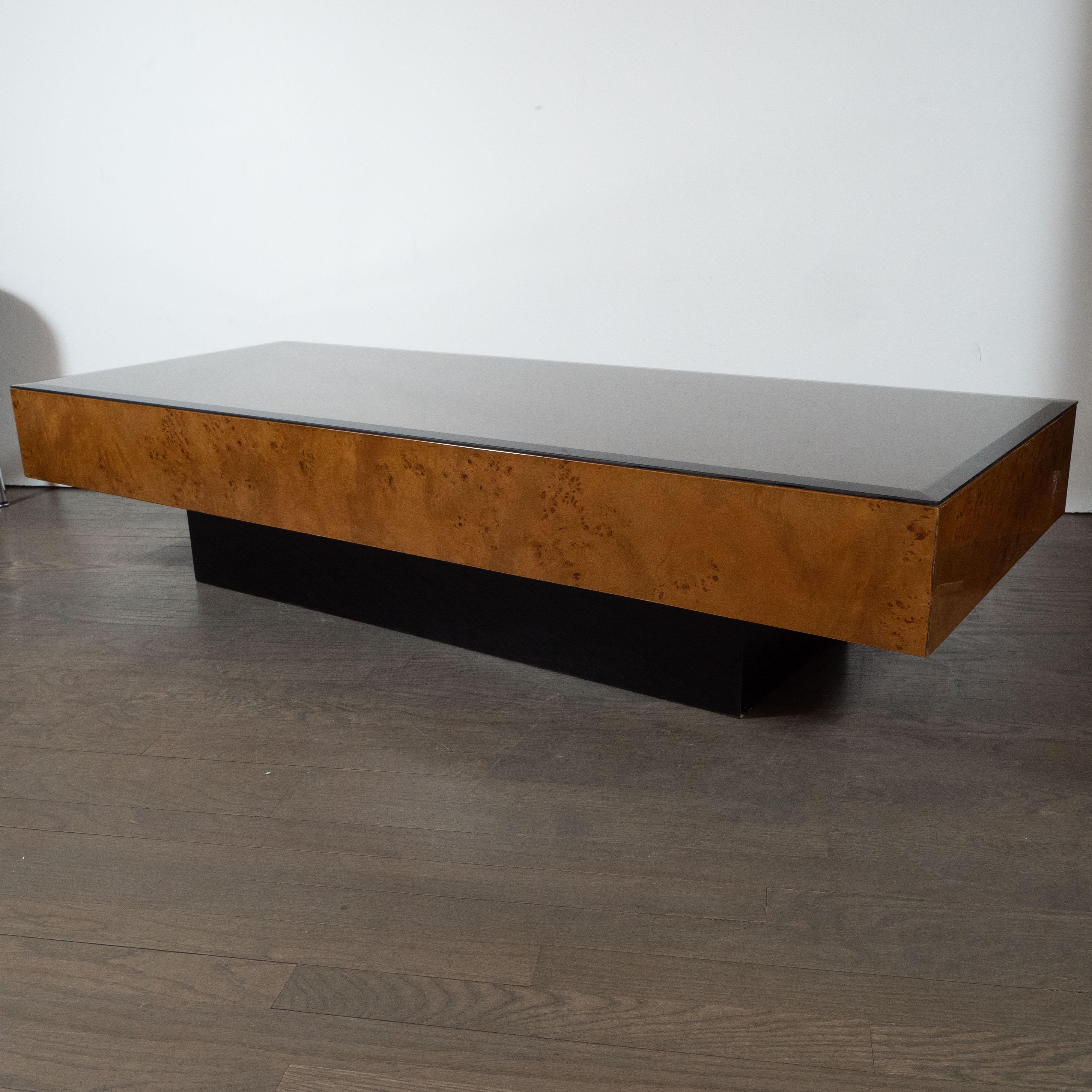 This elegant Mid-Century Modern cocktail table attributed to the esteemed Mid-Century Modern designer Milo Baughman, circa 1970. It features a volumetric rectangular top in bookmatched and burled Carpathian elm with an ebonized walnut base in the