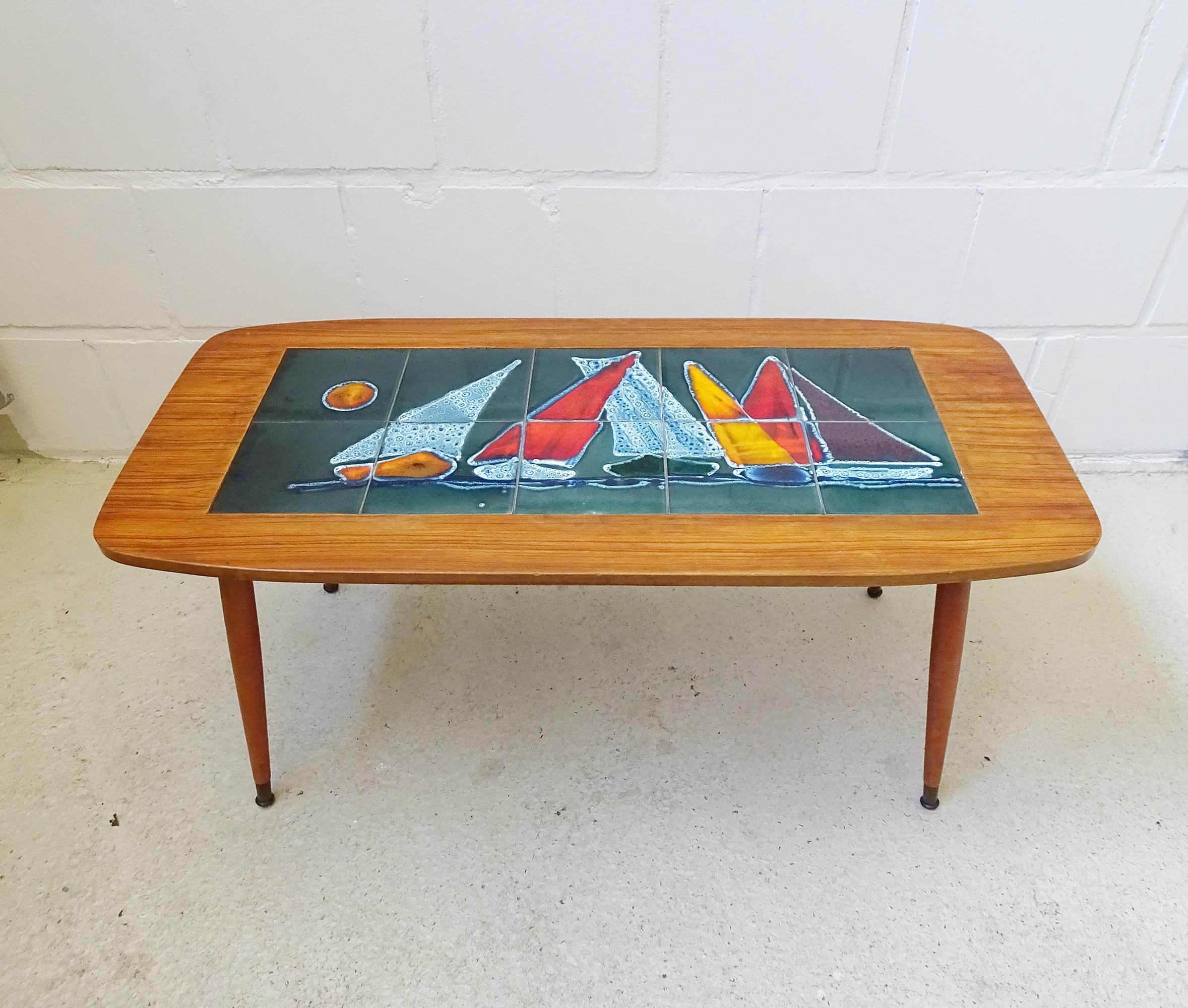 This rectangular table is a stylish coffee table from the 1950s/1960s. The living room table is equipped with a veneered walnut table top and a large tile picture with sailing boats. Artfully designed ceramic tiles in dark green and colorfully