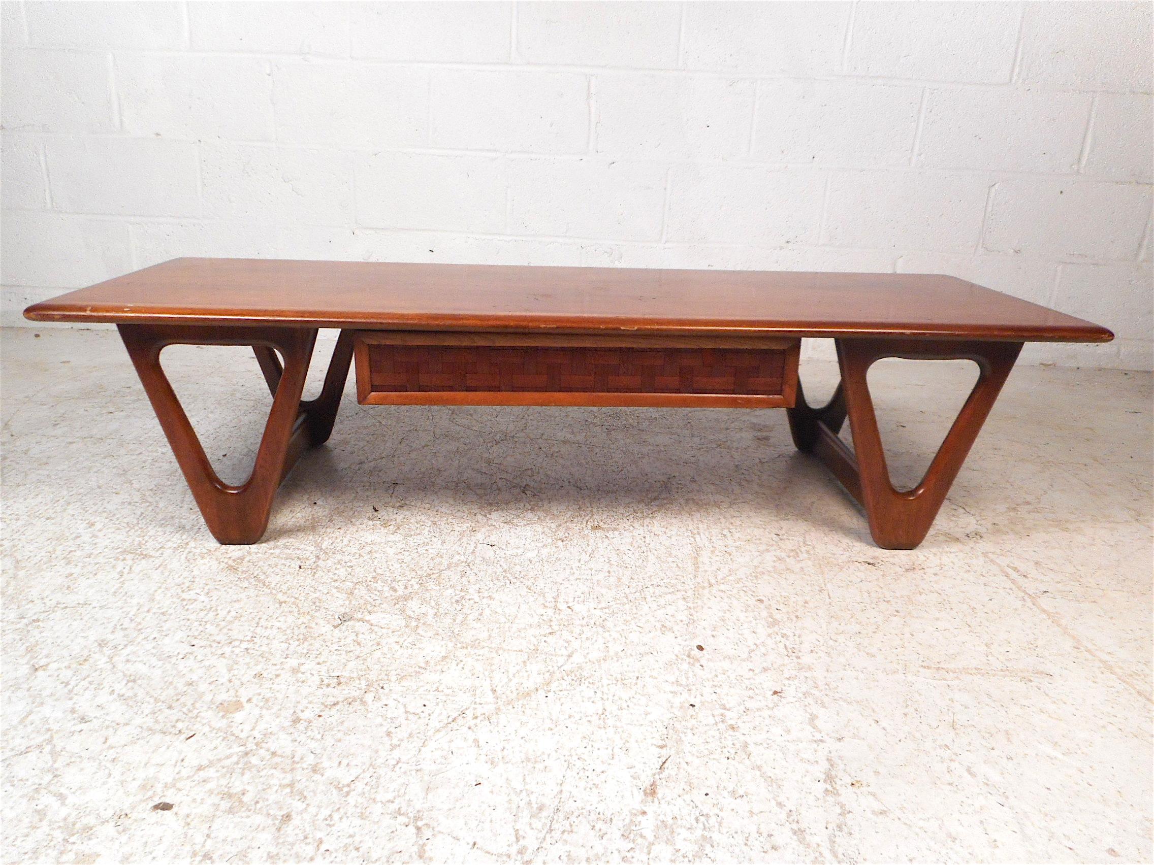 Stylish midcentury coffee table by Lane Furniture Company, circa 1960s. Ample table surface area, uniquely sculpted legs, one drawer under the tabletop with an interesting woven pattern on the drawer-front. This table would make a handsome addition