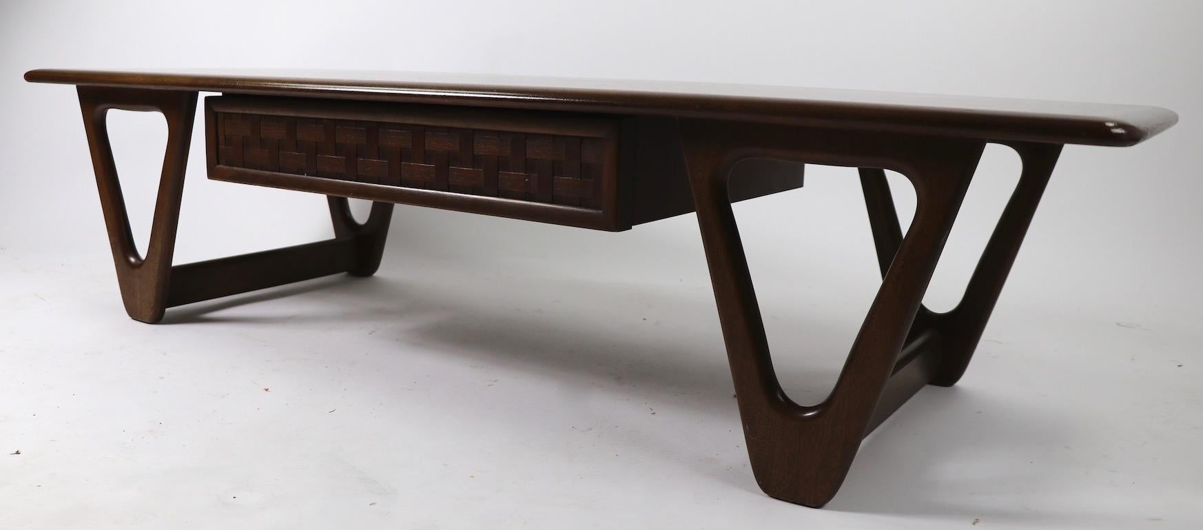 Classic Mid-Century Modern coffee table, perception line, manufactured by Lane Furniture. The table has one drawer with a weave pattern front, hairpin legs and a solid board top. This example is in good original condition but does show some cosmetic