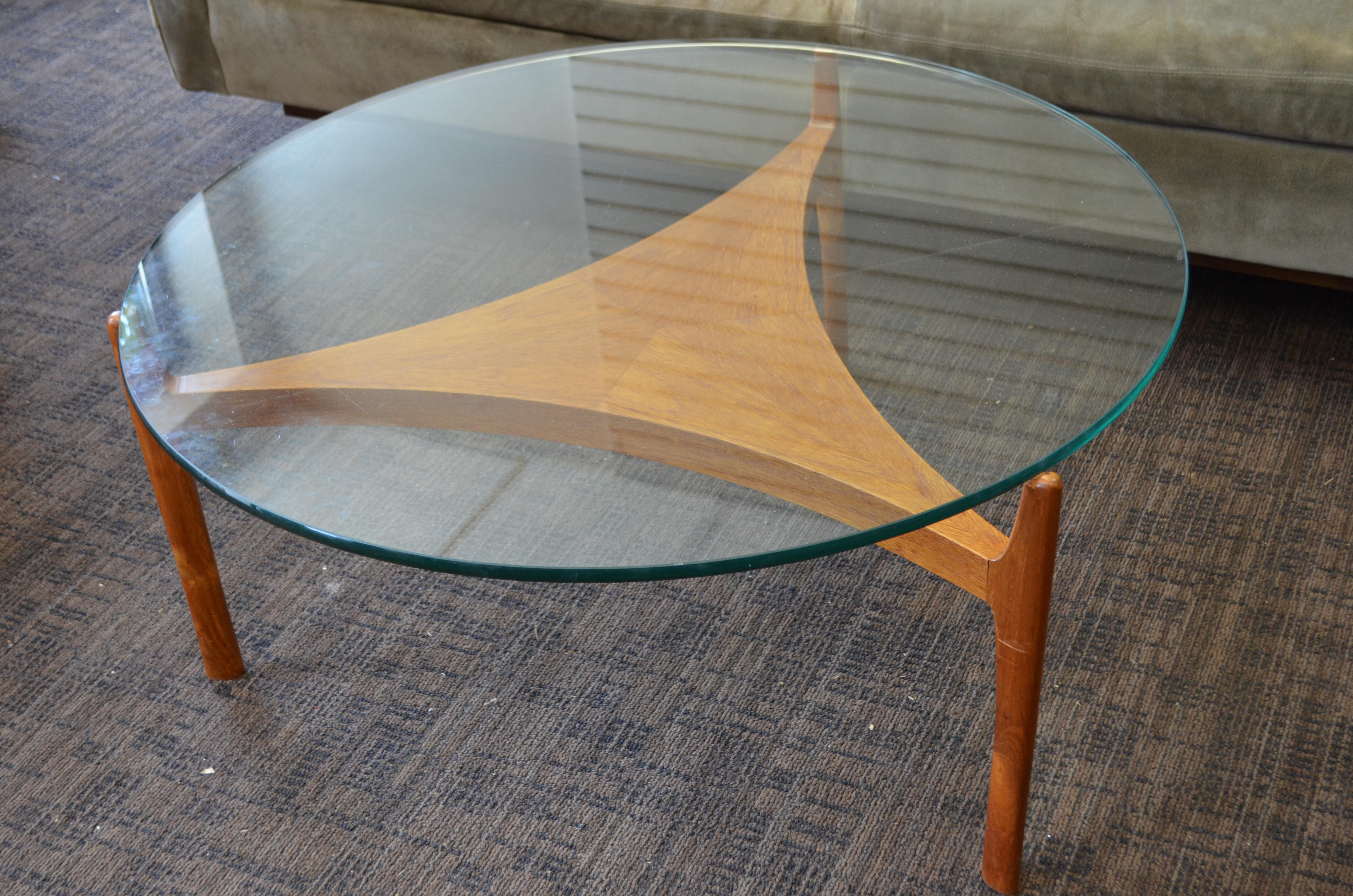 Midcentury coffee table, low table with triangular teak base and glass top. Designed by Sven Ellekaer of Denmark. Glass top notches neatly into the triangular teak base with its book-matched parquetry center. Shows through the glass with a