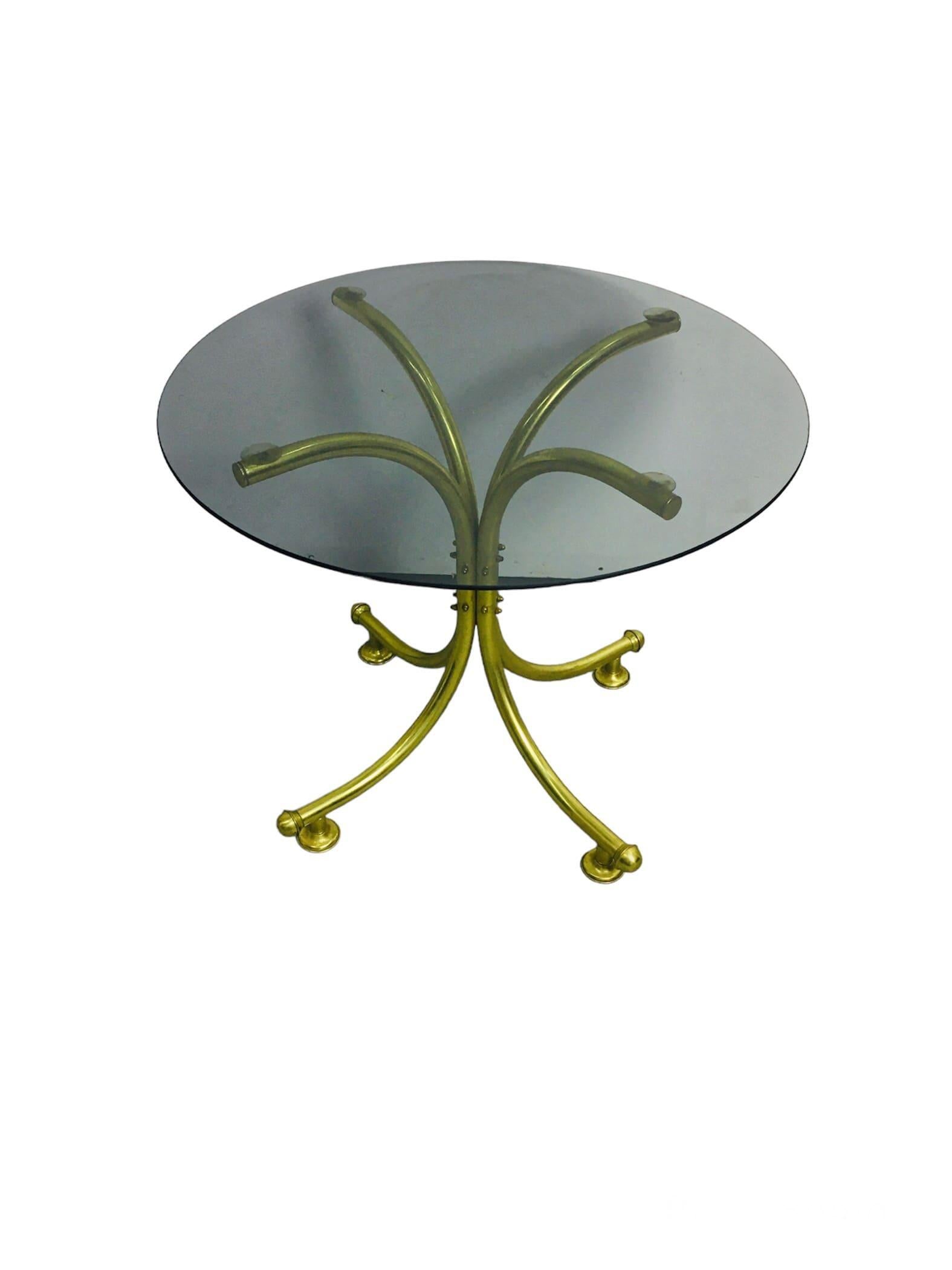 Unique coffee table with bent copper legs and darkened circular tempered glass tabletop, from the 60s and 70s. This quality piece is available in beautiful condition. A truly decorative piece with shiny brass legs. Available in good condition,