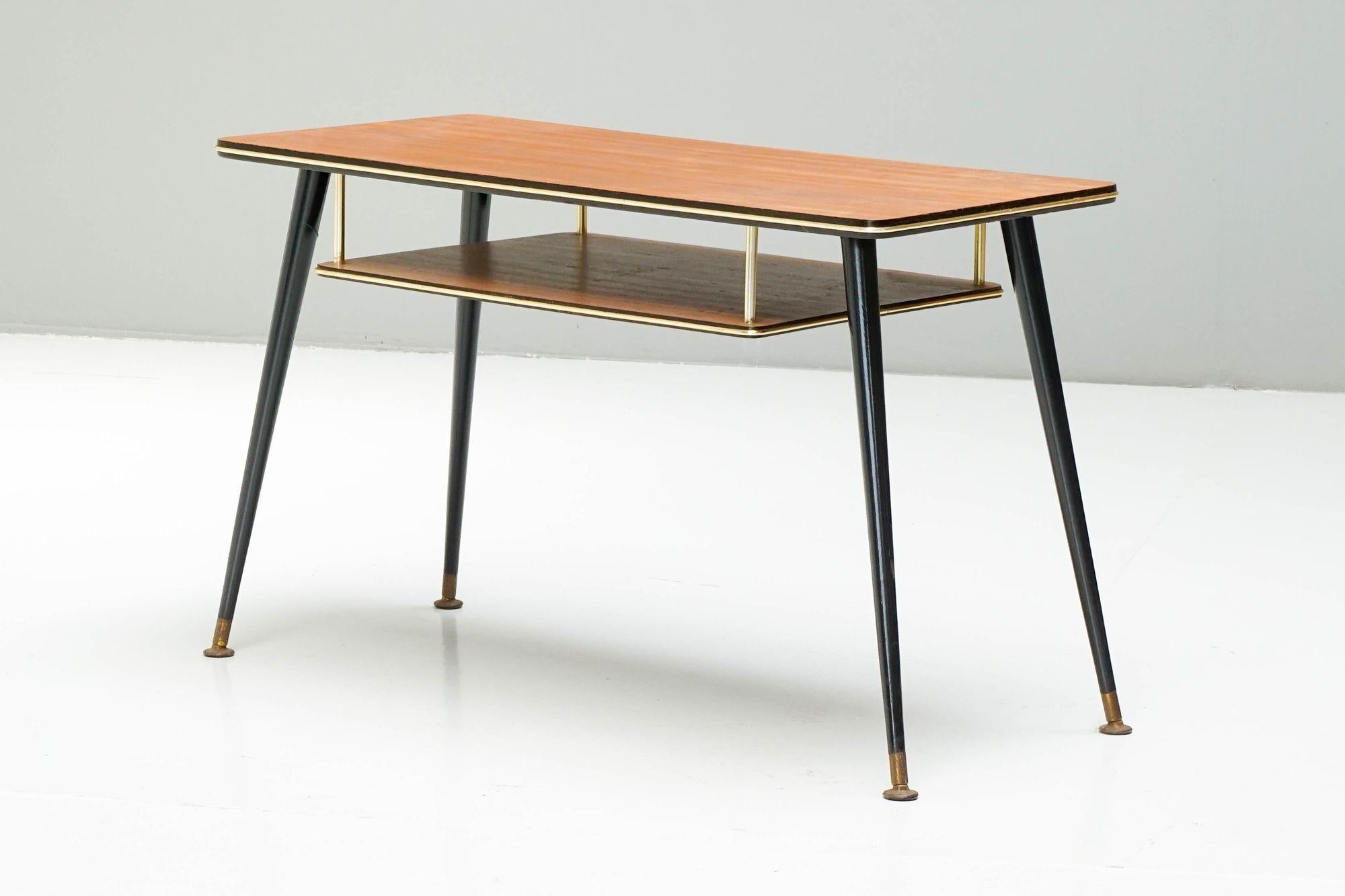 Table basse du milieu du siècle dernier avec porte-revues suspendu. Pieds noirs, plateau en placage de noyer et pieds en laiton.