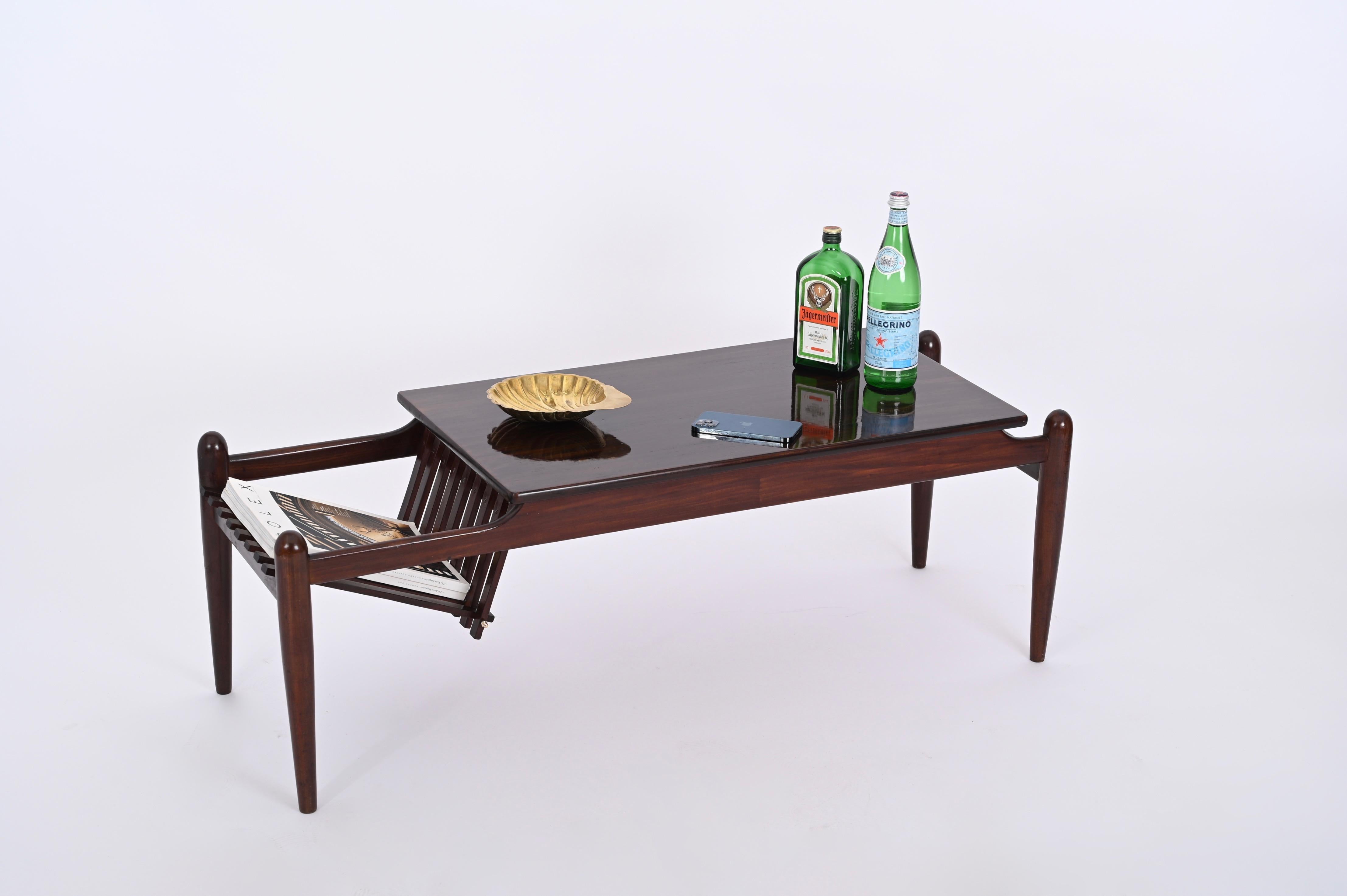 Magnifique table basse avec porte-revues latéral en teck foncé, produite en Italie dans les années 60 dans le style d'Ico Parisi.

Le ton bois du plateau est tout simplement étonnant et la particularité de l'élégant porte-revues avec des finitions