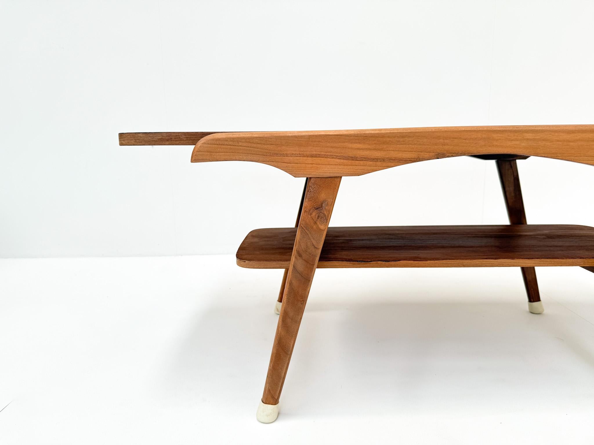 Rara mesa de centro de mediados de siglo con un versátil tablero reversible. Una cara está acabada en cálida chapa de teca, que resalta las vetas naturales de la madera, mientras que la otra tiene una superficie lisa de fórmica, práctica y fácil de