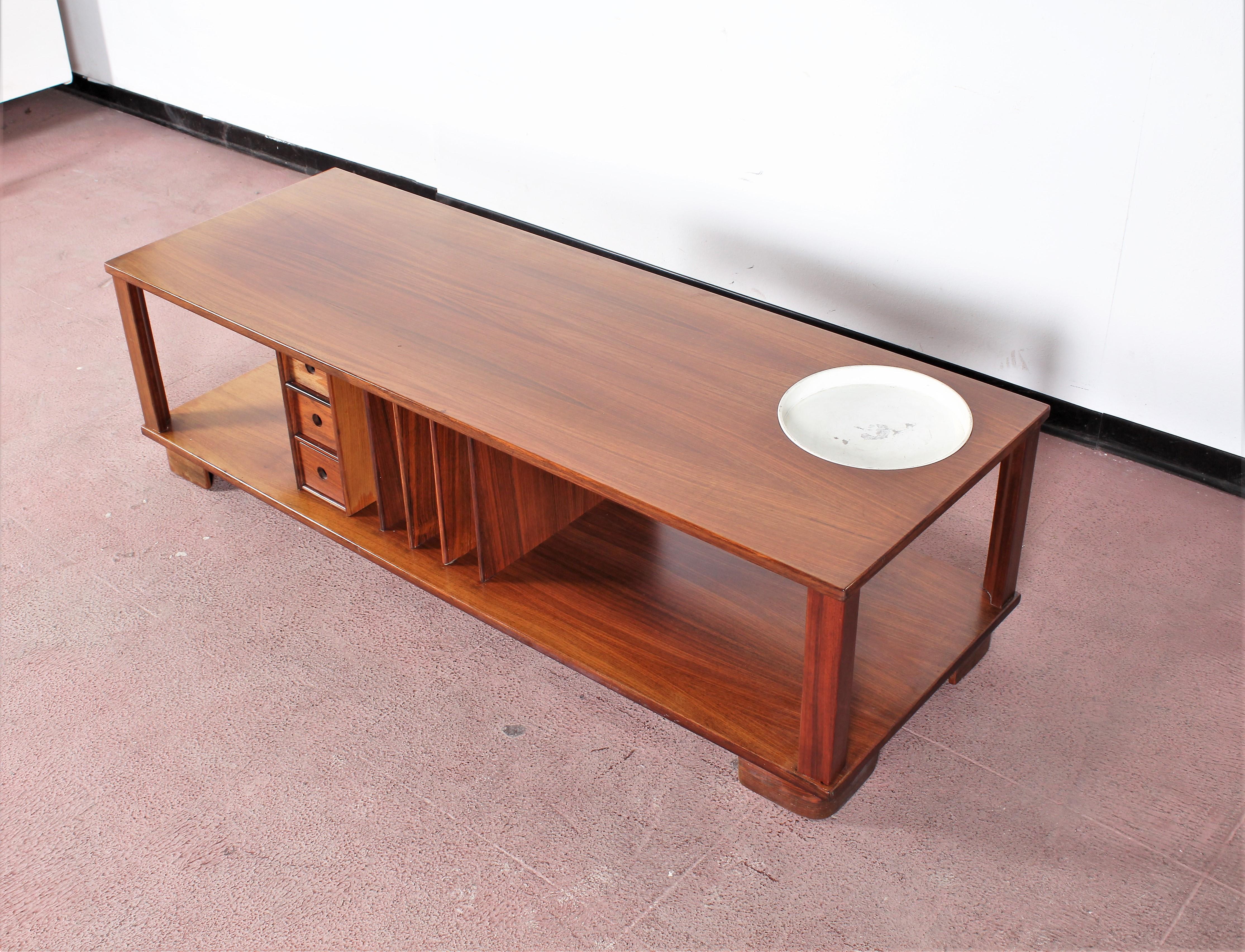 Beautiful 1960s coffee table, Danish Minimalist design. Teak finishes. Side-to-side vertical compartments, magazine or book stands, three small rectangular drawers, which can be edged on both sides, and a removable circular metal tray. Kept in good