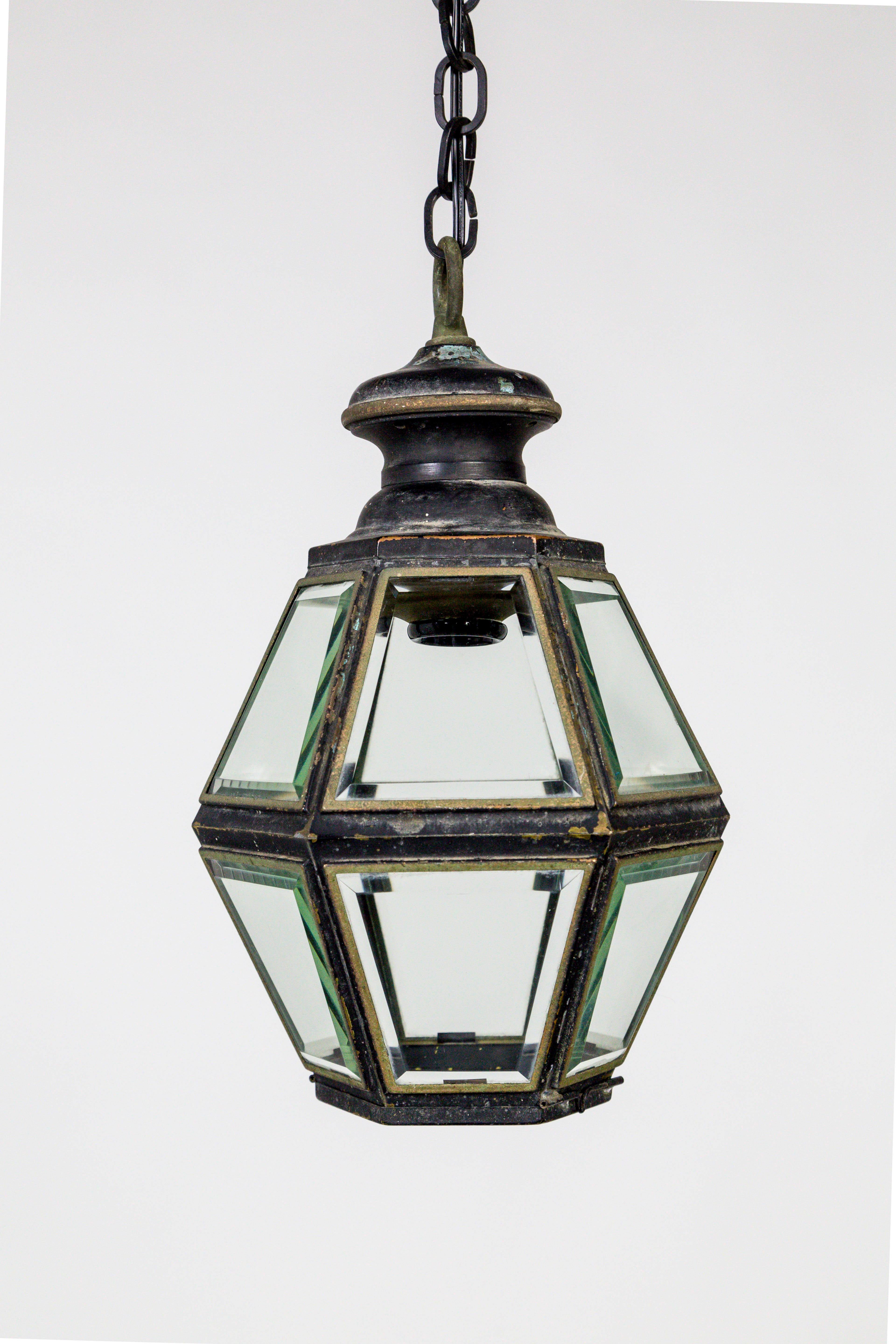 Wonderful 1950s, American Colonial Revival style, hexagon, metalwork lanterns. Completely closed with beautiful, beveled glass; the bottom panel is etched with a flower shape, and opens to change the bulb; multiple paint layers and copper green