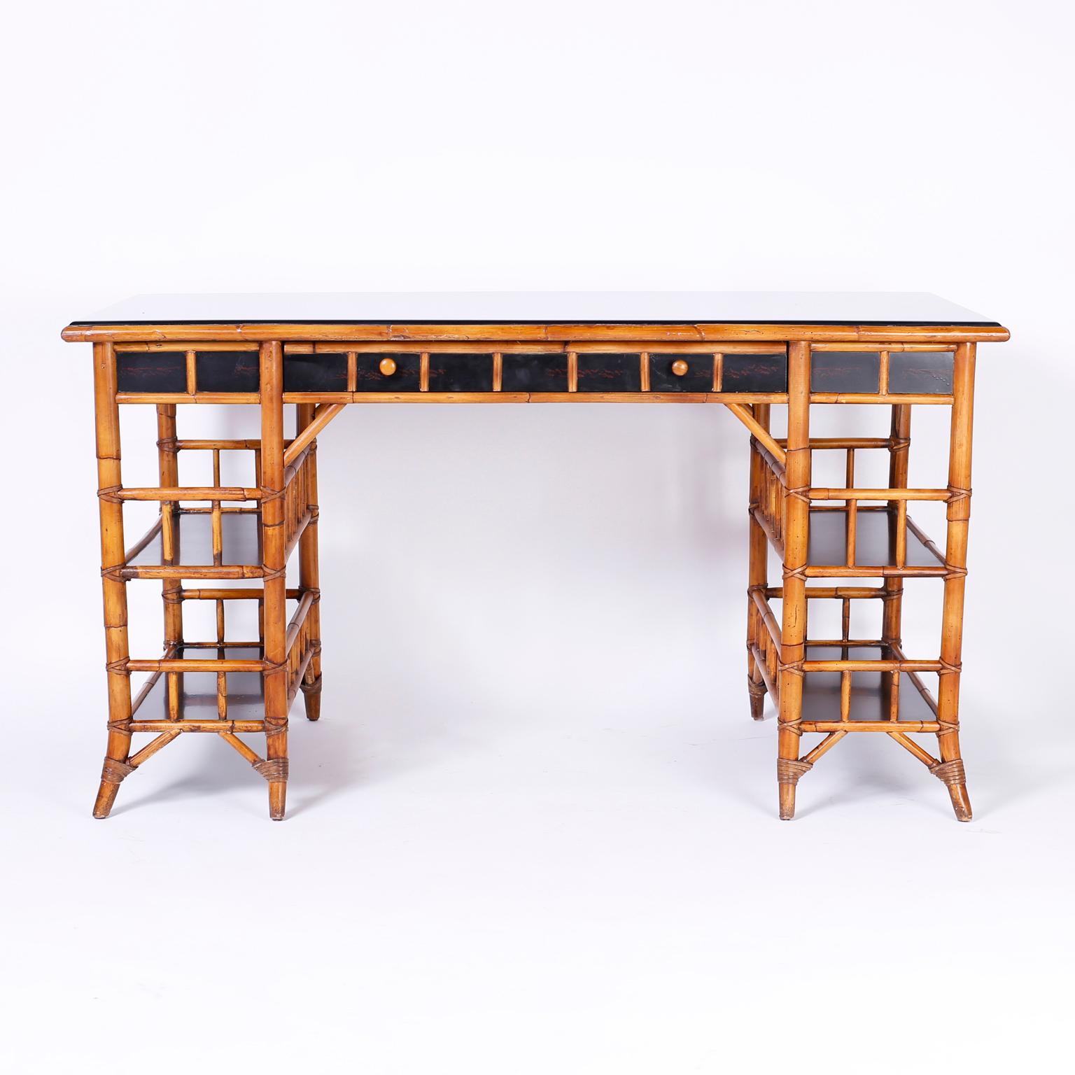 British colonial style midcentury bamboo desk with a black lacquered top, sides and storage surfaces. Signed Milling Road a division of Baker furniture.