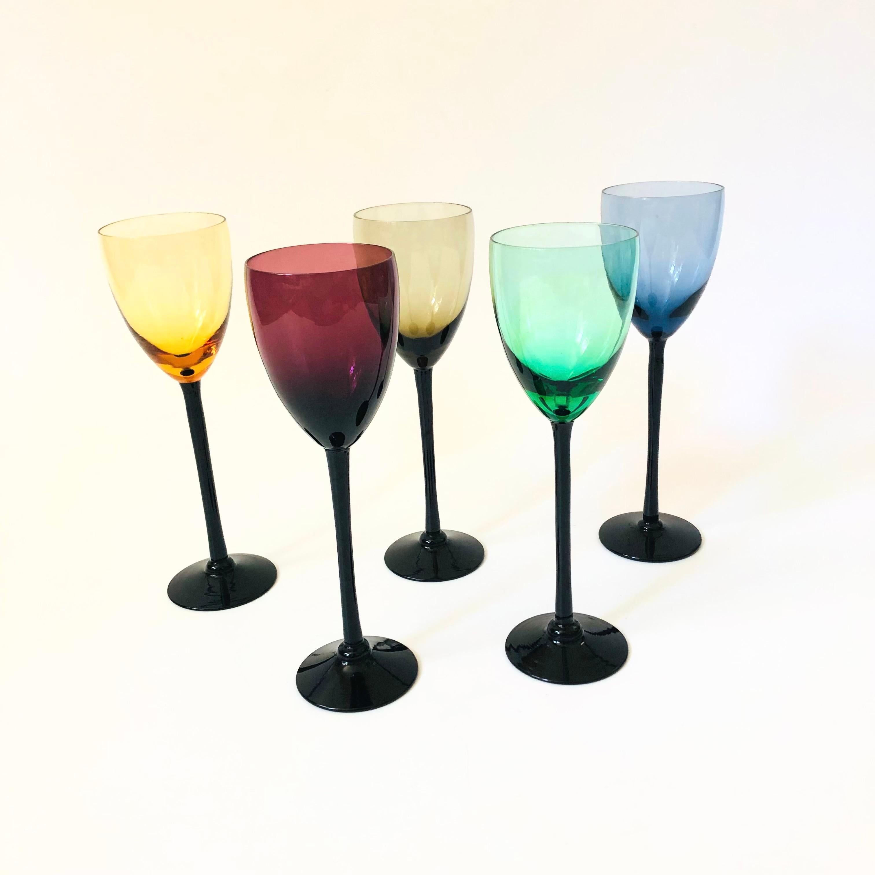 A set of 5 mid century cordials glasses each in a different color with black stems.

