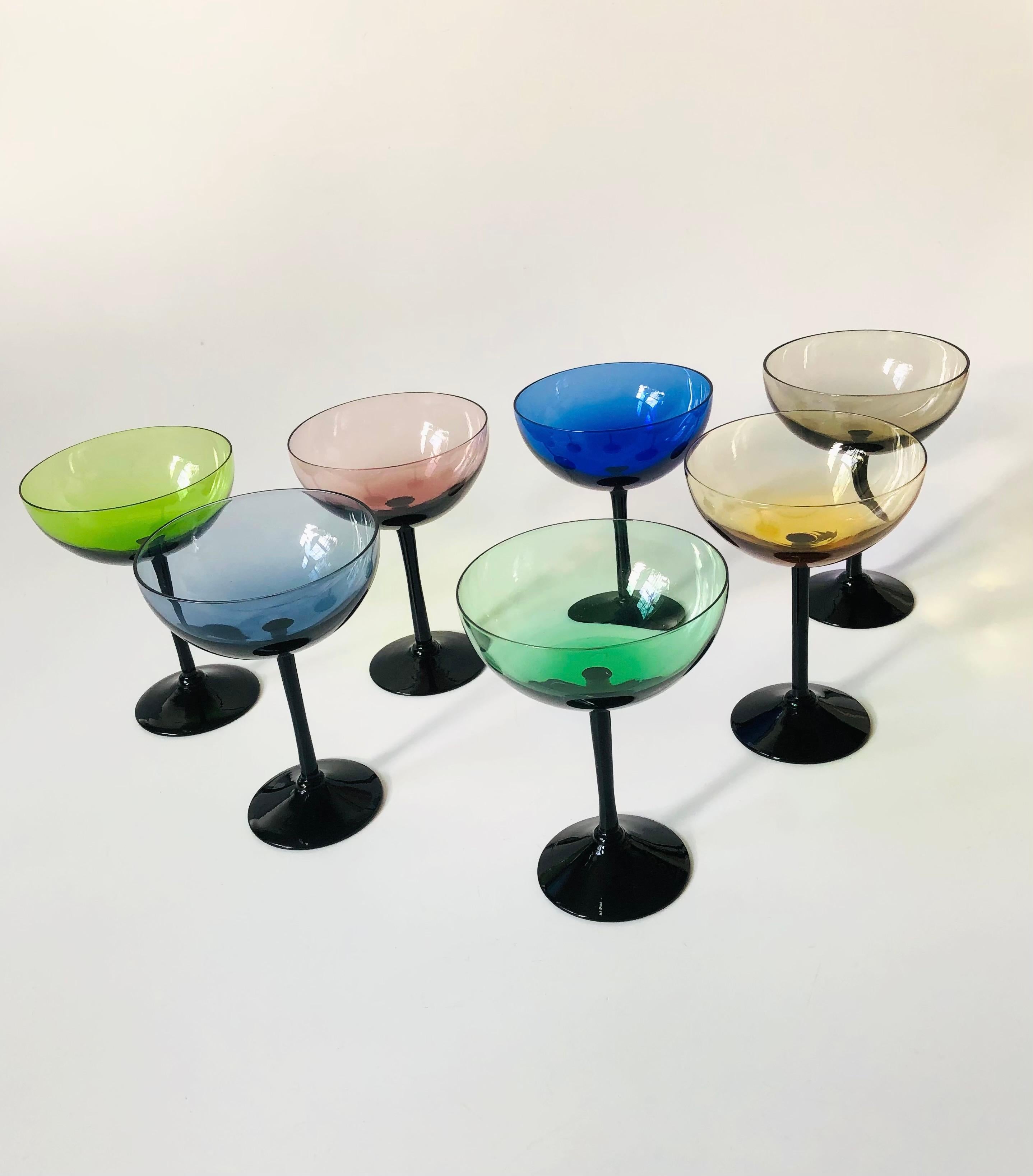 A set of 7 midcentury coupe glasses each in a different color with black stems. Perfect for serving champagne.

   