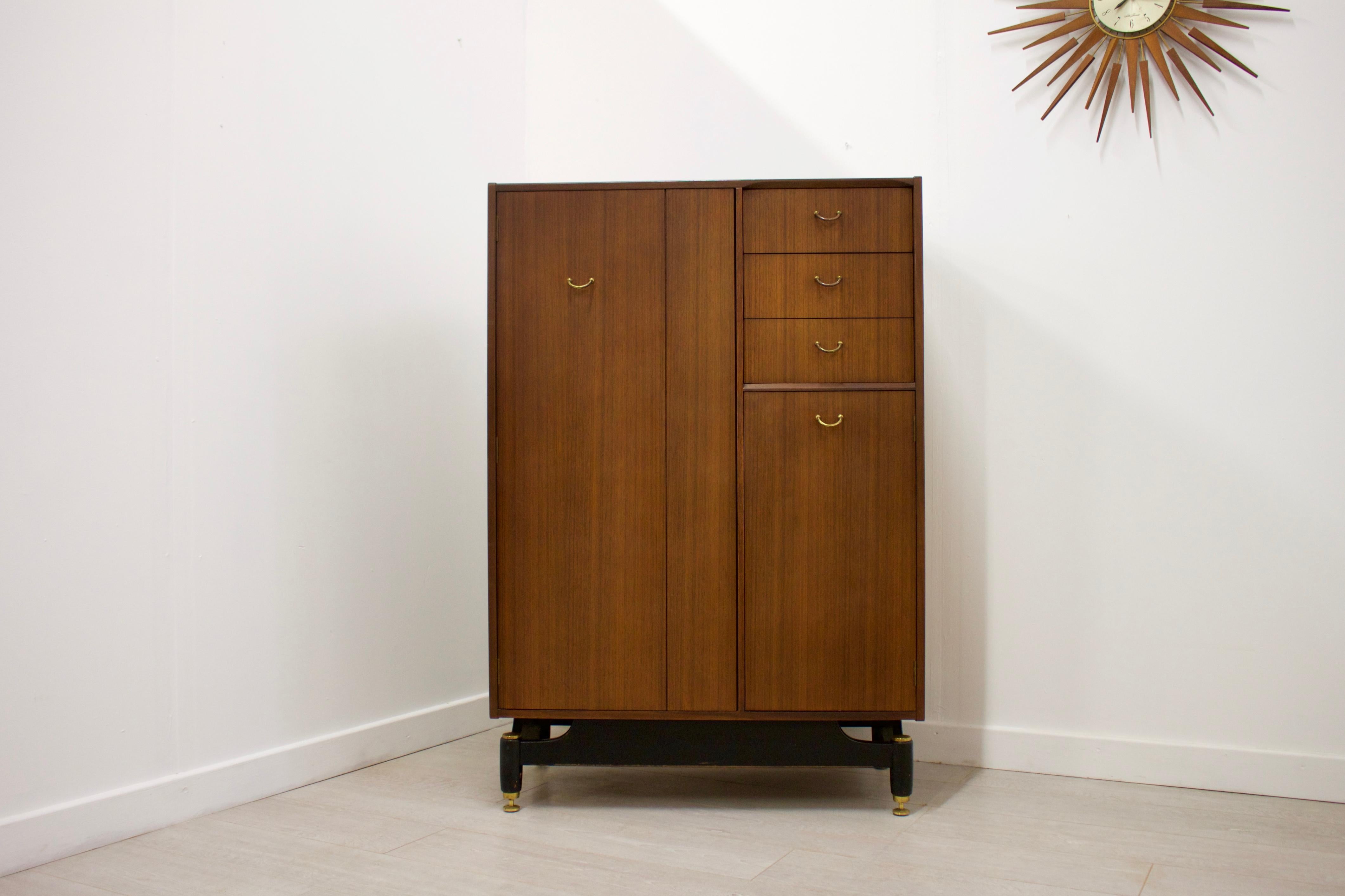 - Mid-Century Modern wardrobe
- Manufactured by G-Plan
- Made from Afromosia
- Features a pull-out hanging rail inside the left cupboard, 2 shelves in the bottom right cupboard and 3 drawers.
- The top drawer includes a pop-up mirror and is
