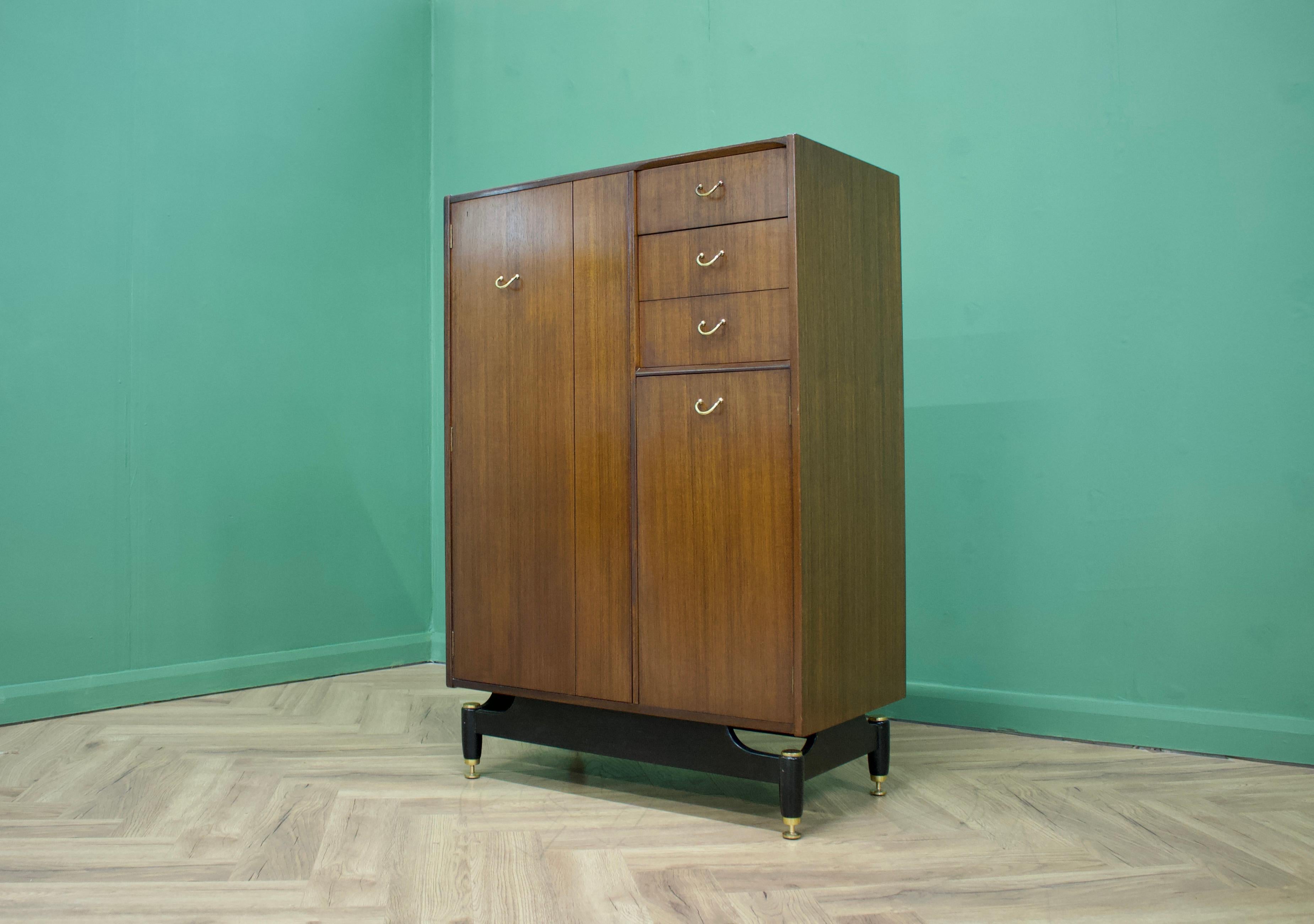 Mid century modern compact wardrobe (Compactum).
Manufactured by G-Plan in the UK. 
Features a pull-out hanging rail inside the left cupboard, 1 shelf in the bottom right cupboard and 3 drawers.
 