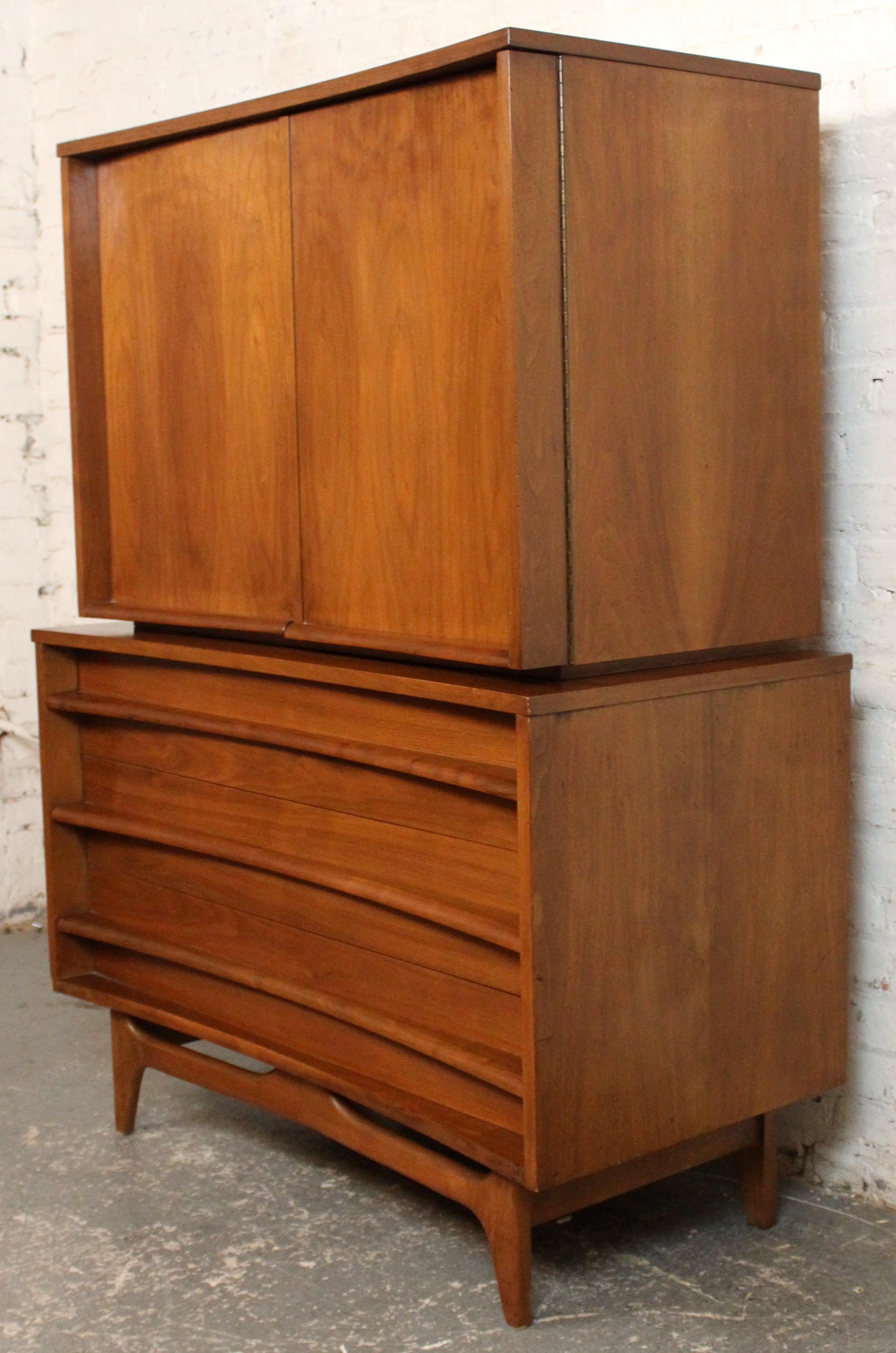 Bellissimo comò highboy in due pezzi della metà del secolo scorso di Young Manufacturing Co. realizzato in noce riccamente sgrossato con i frontali dei cassetti scolpiti tipici del marchio. Con sei cassetti spaziosi e linee pulite e moderne, questo