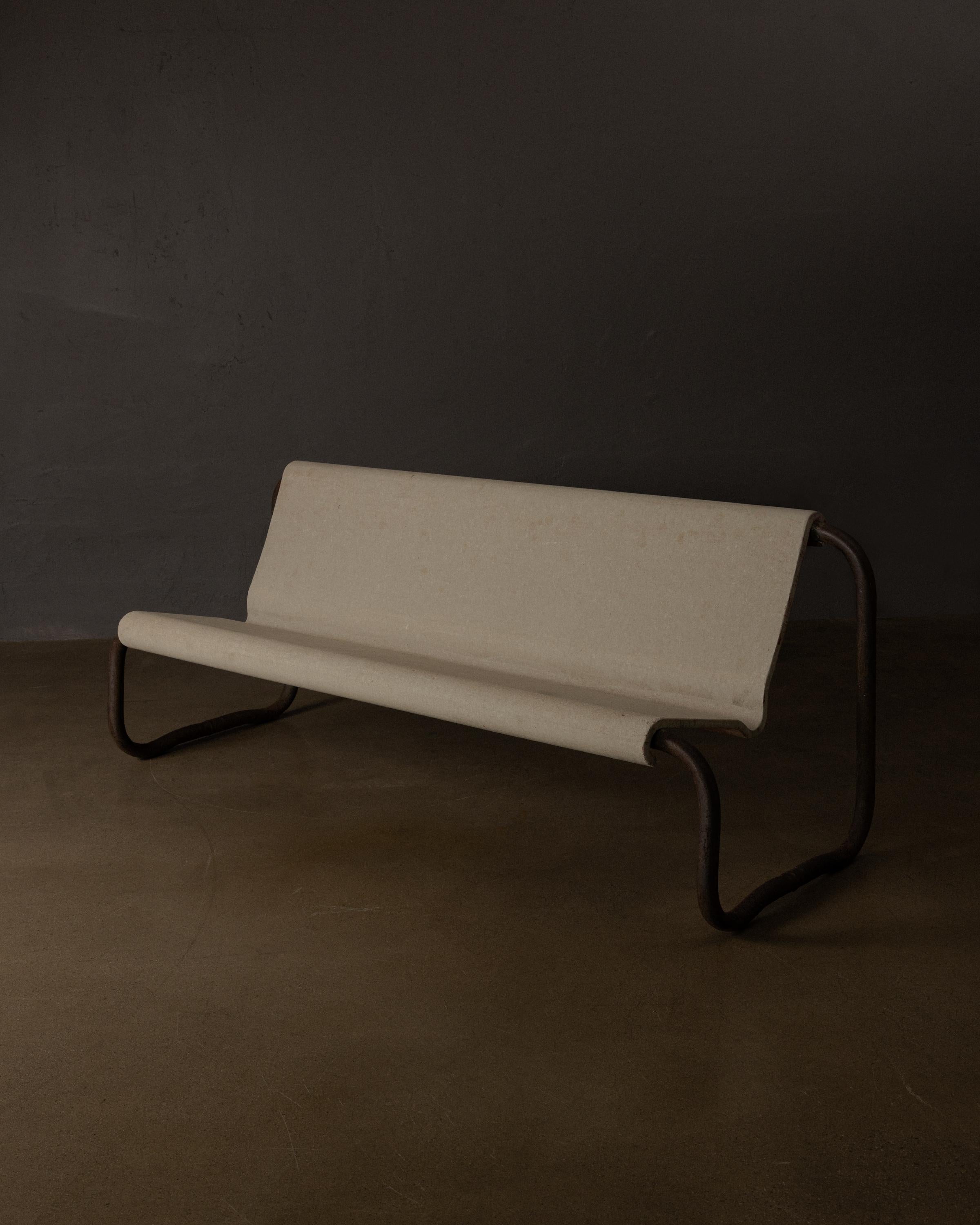 Este banco escultórico de Willy Guhl, un raro ejemplo del diseño modernista suizo, presenta un asiento de fibrocemento elegantemente curvado que se apoya en una base continua de hierro tubular con pátina original. El uso que hace Guhl de materiales
