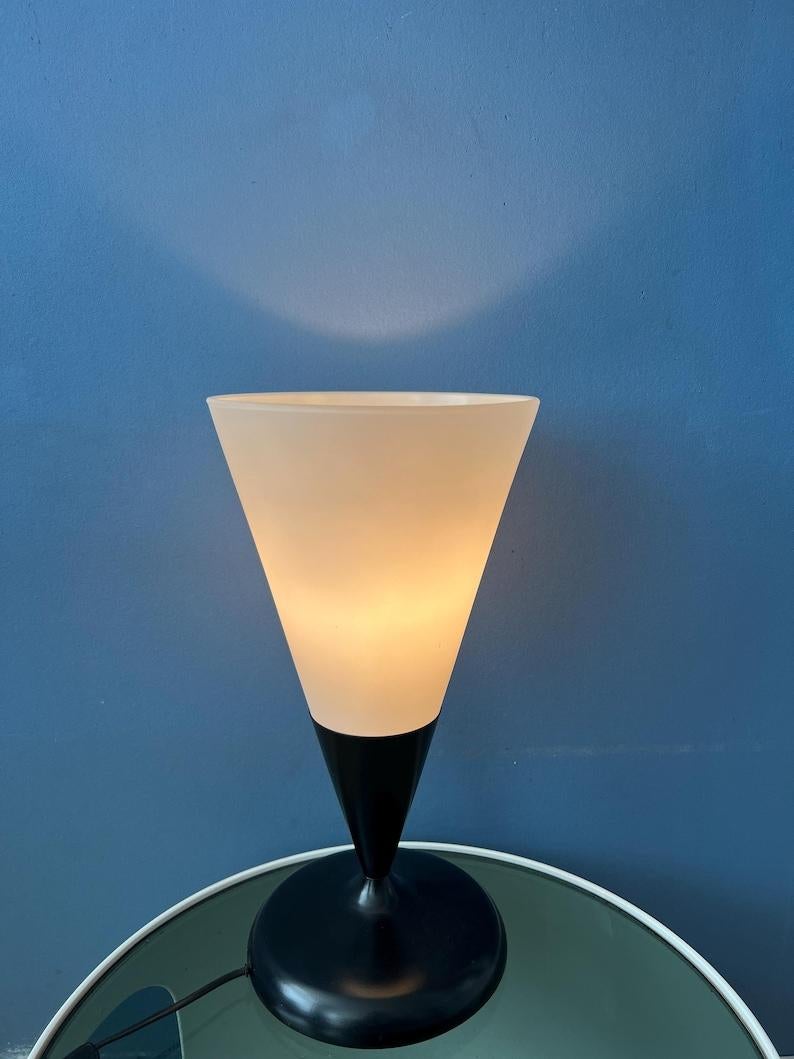 Opaline glass table in cone shape with black metal base and milk glass scone. The lamp is pretty large in size. The lamp requires one E27/26 (standard) lightbulb and currently has an EU-plug.

Additional information:
Materials: Glass, metal
Period: