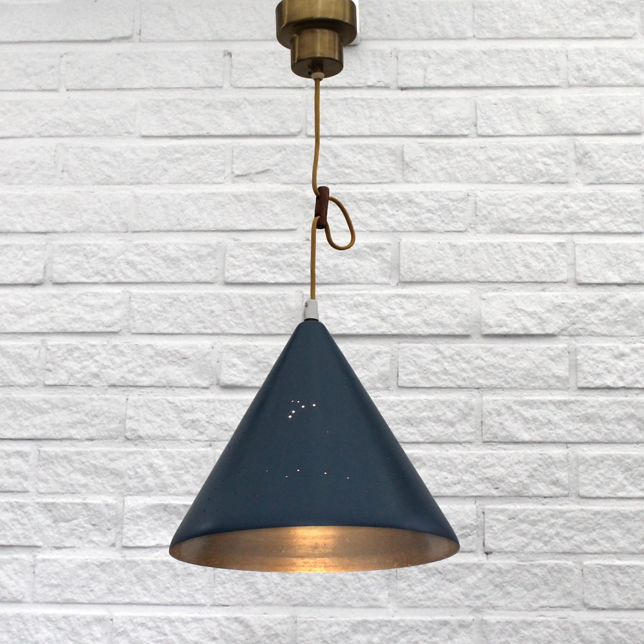 Swedish mid-century cone-shaped pendant lamp with intricate star constellations and a crescent moon perforated in the metal. It features a wooden cable shortener and a brass canopy. This lamp stands as a beautiful example of Scandinavian playful