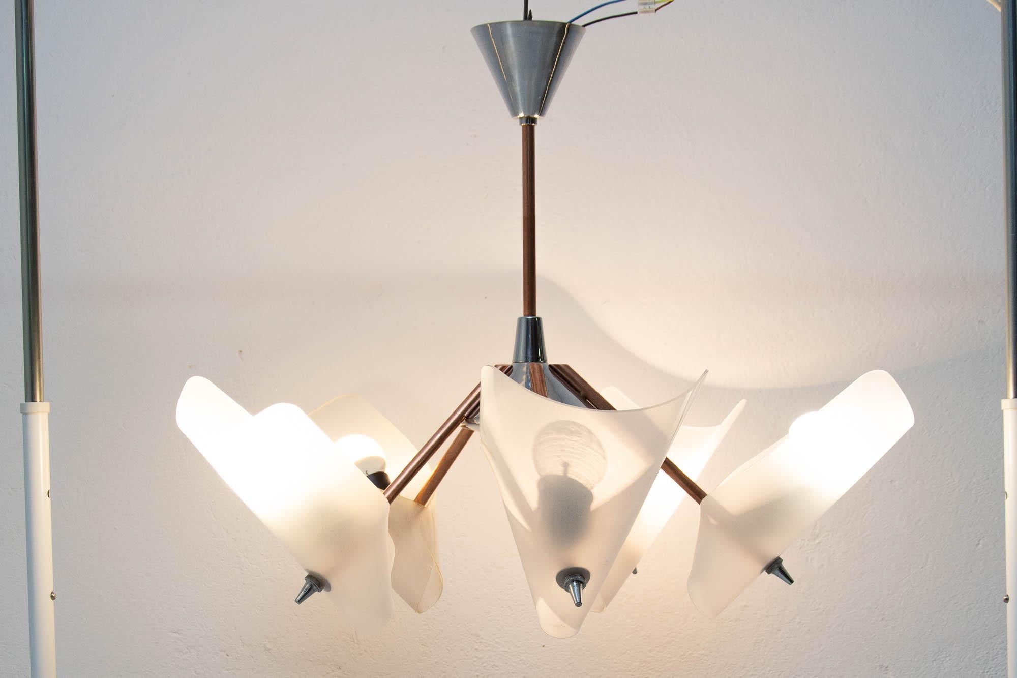This nice pendant chandelier was made by Czechoslovak company Drukov in the 1950s. It features a brass and chrome structure with five arrows-shaped rods on which 5 plastic conic shades are mounted. The chandelier was completely cleaned and newly