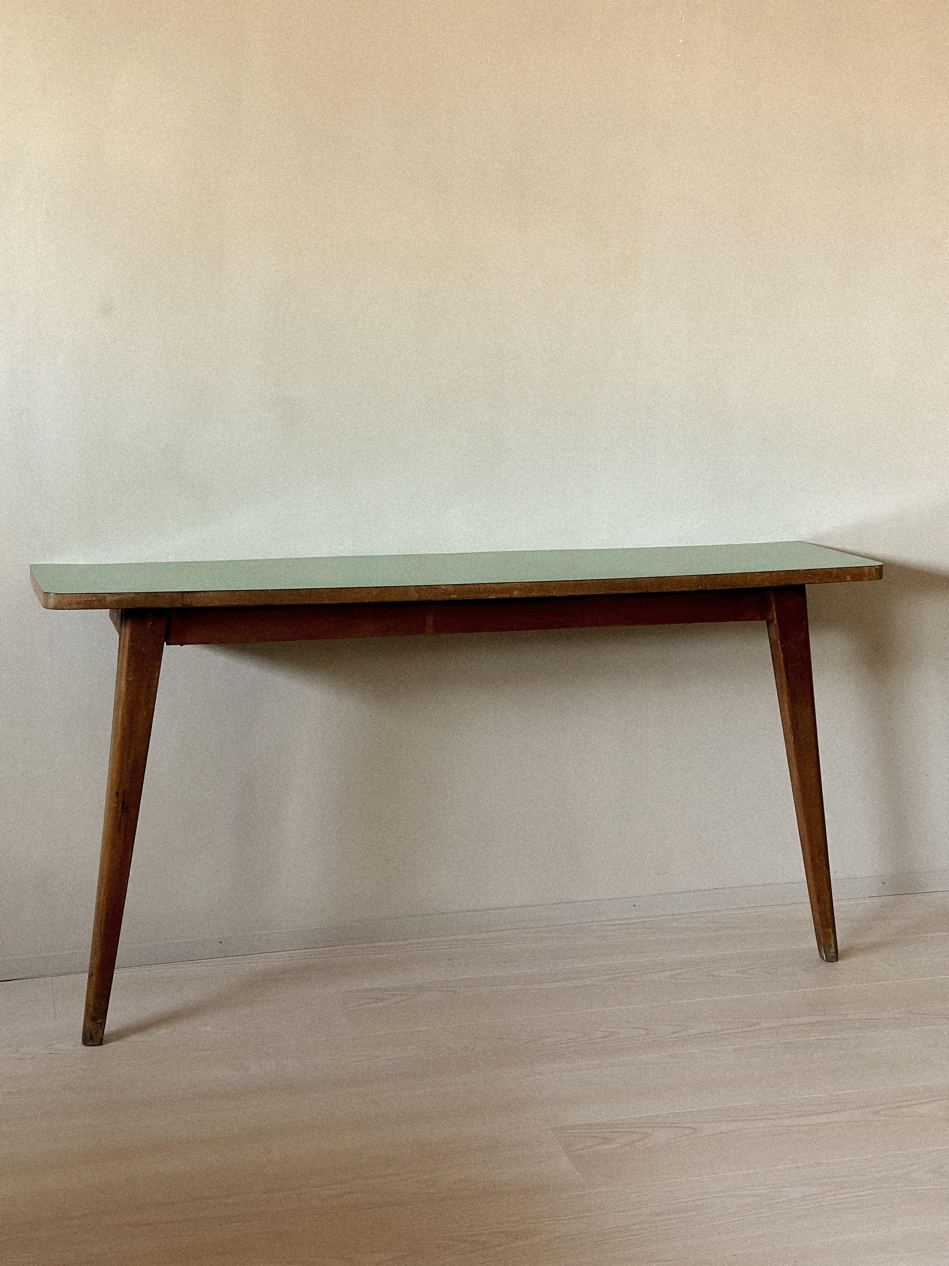 Mid-Century console table with tapered legs and original green Formica top. Wear consistent with age and use. Must be wall-mounted with screws for stability.
