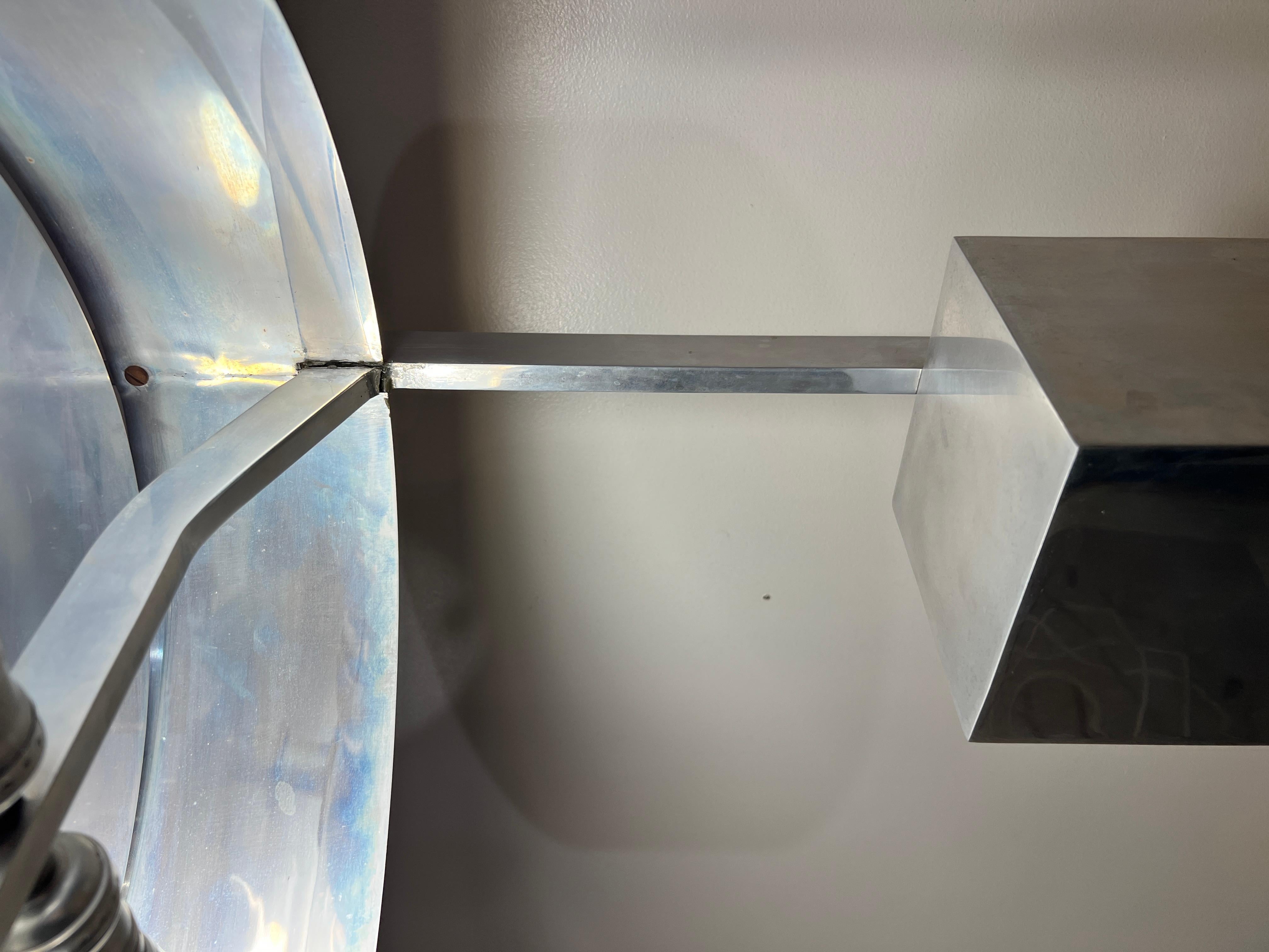 Lampe de table en aluminium, solide et spectaculaire. Bloc rectangulaire surmonté d'un abat-jour circulaire.