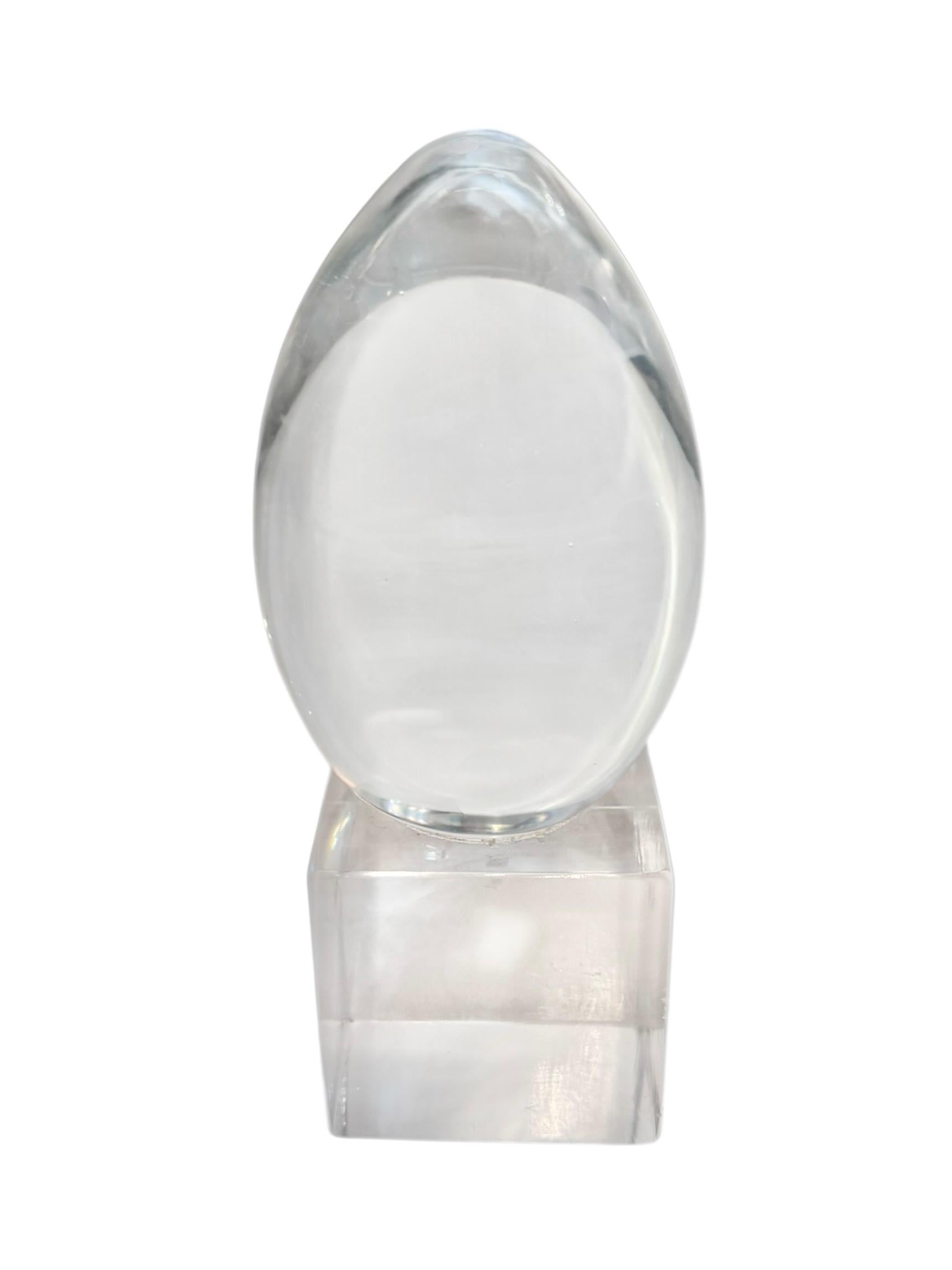 Questa scultura a forma di uovo in lucite, moderna e di metà secolo, colpisce per la sua semplicità ed è una miscela magistrale di forma organica e precisione geometrica. La forma superiore a uovo, splendidamente realizzata in lucite trasparente,