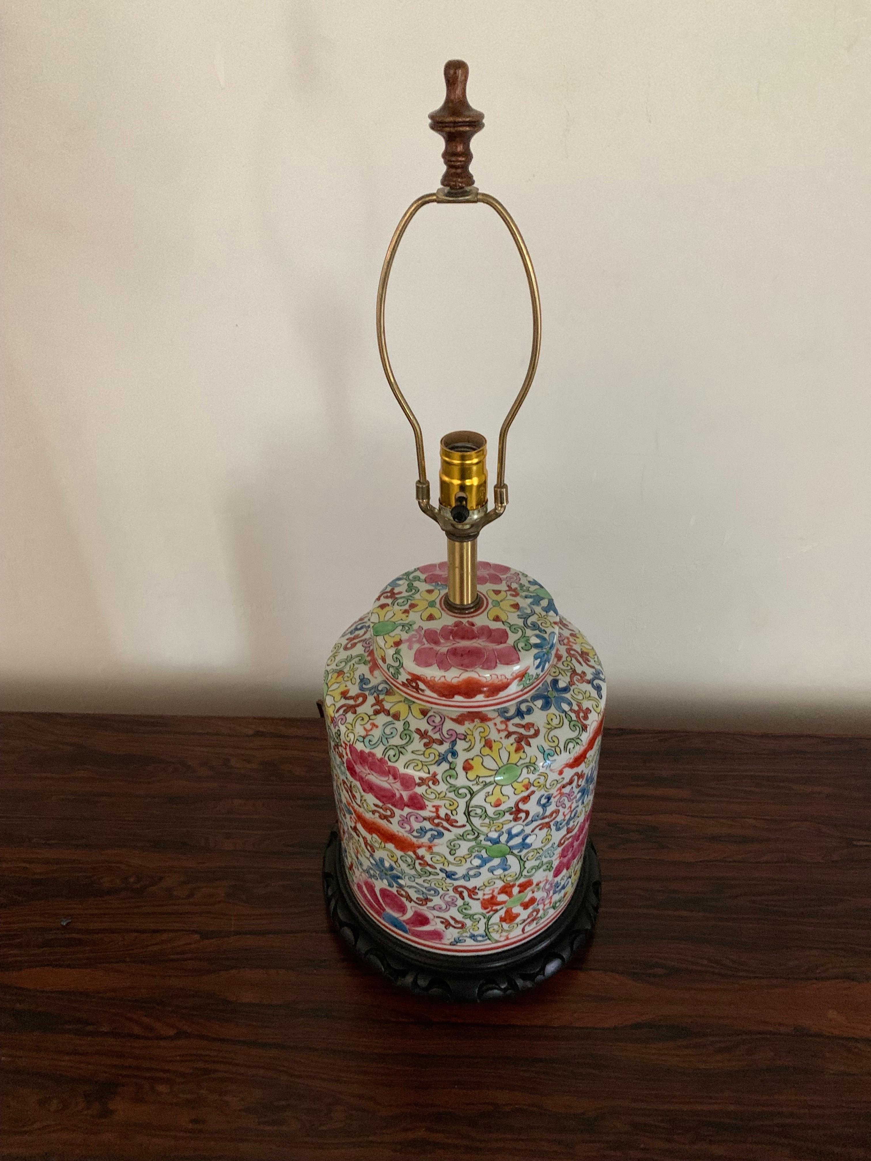Beautiful and colorful vintage Chinese ginger jar that has been converted into a lap. The ginger jar is two pieces; vase and lid. Sits upon a dark wooded base. Ginger jar is masterfully hand painted in vibrant yellows, blues, and reds on a white