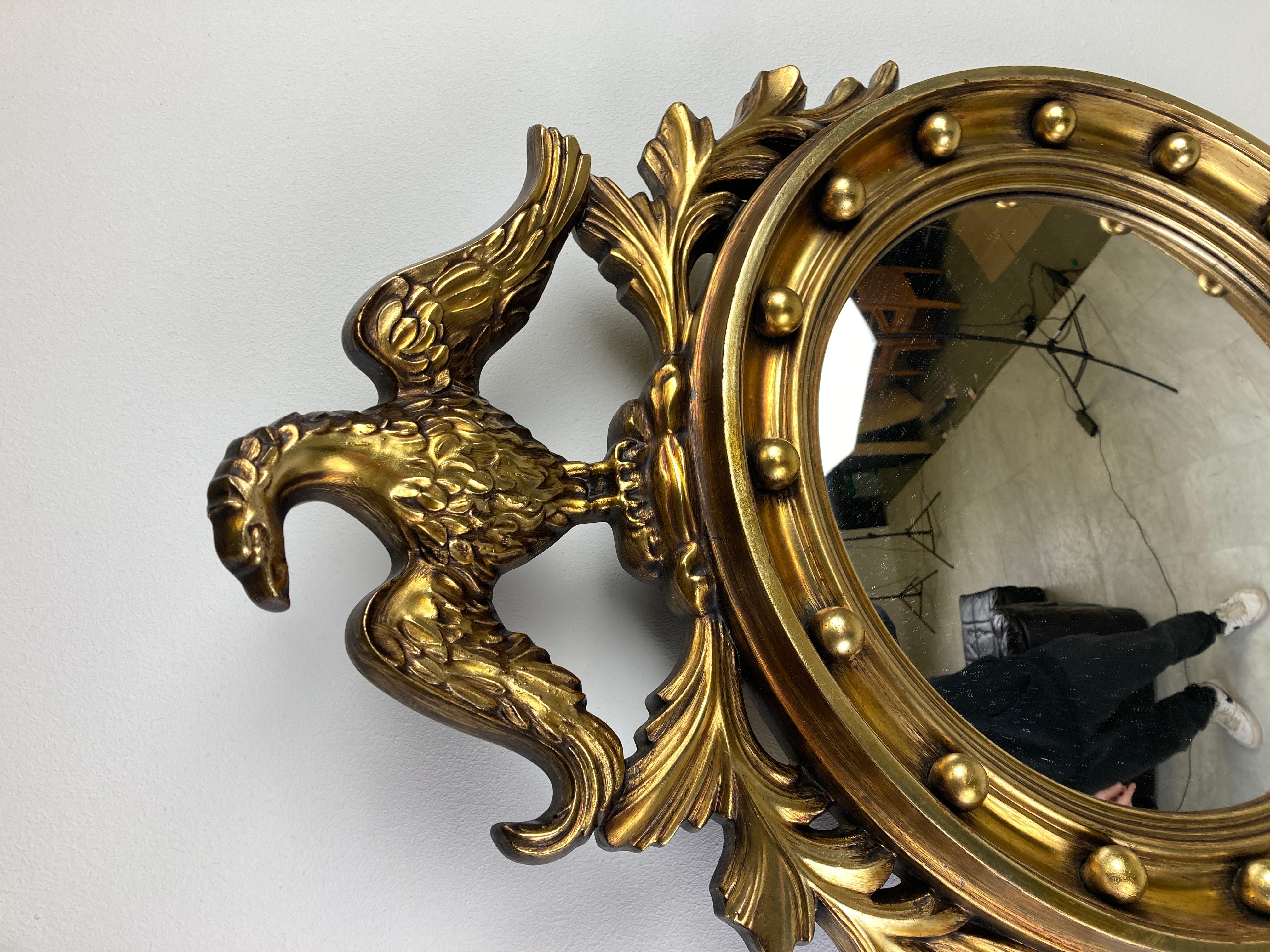 Gilded resin convex mirror with an eagle - sometimes referred to as 'butler' mirror or 'witch eye' mirror.

The golden mirror is in a very good condition.

Beautiful eye catching mirror, ideal to add to a collection of sunburst mirrors.

1960s