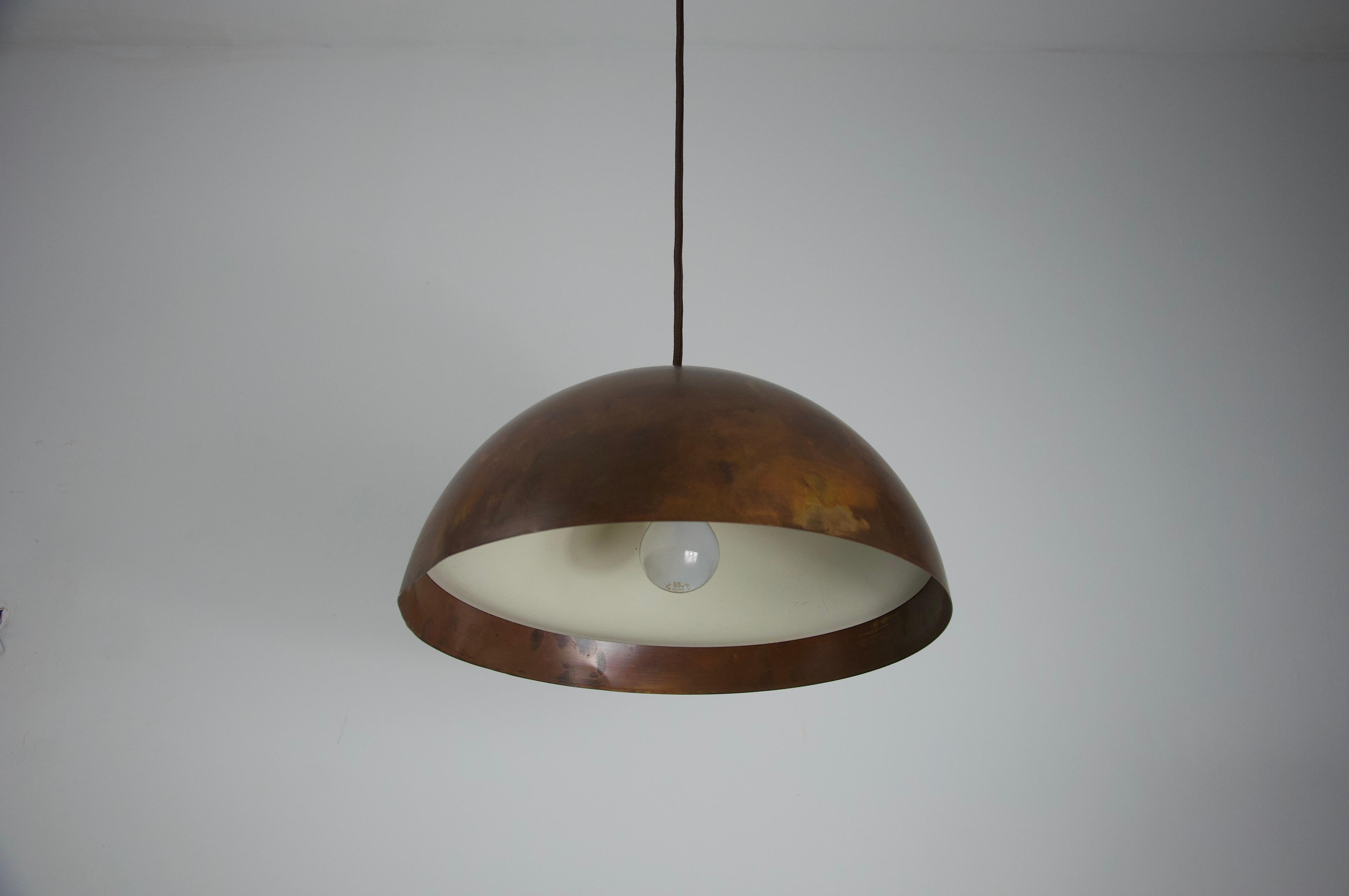 This striking mid-century ceiling lamp was crafted in Italy during the 1960s and exemplifies the elegant simplicity of the era’s design aesthetic. The lamp features a beautifully aged copper dome shade with a warm, natural patina that highlights its
