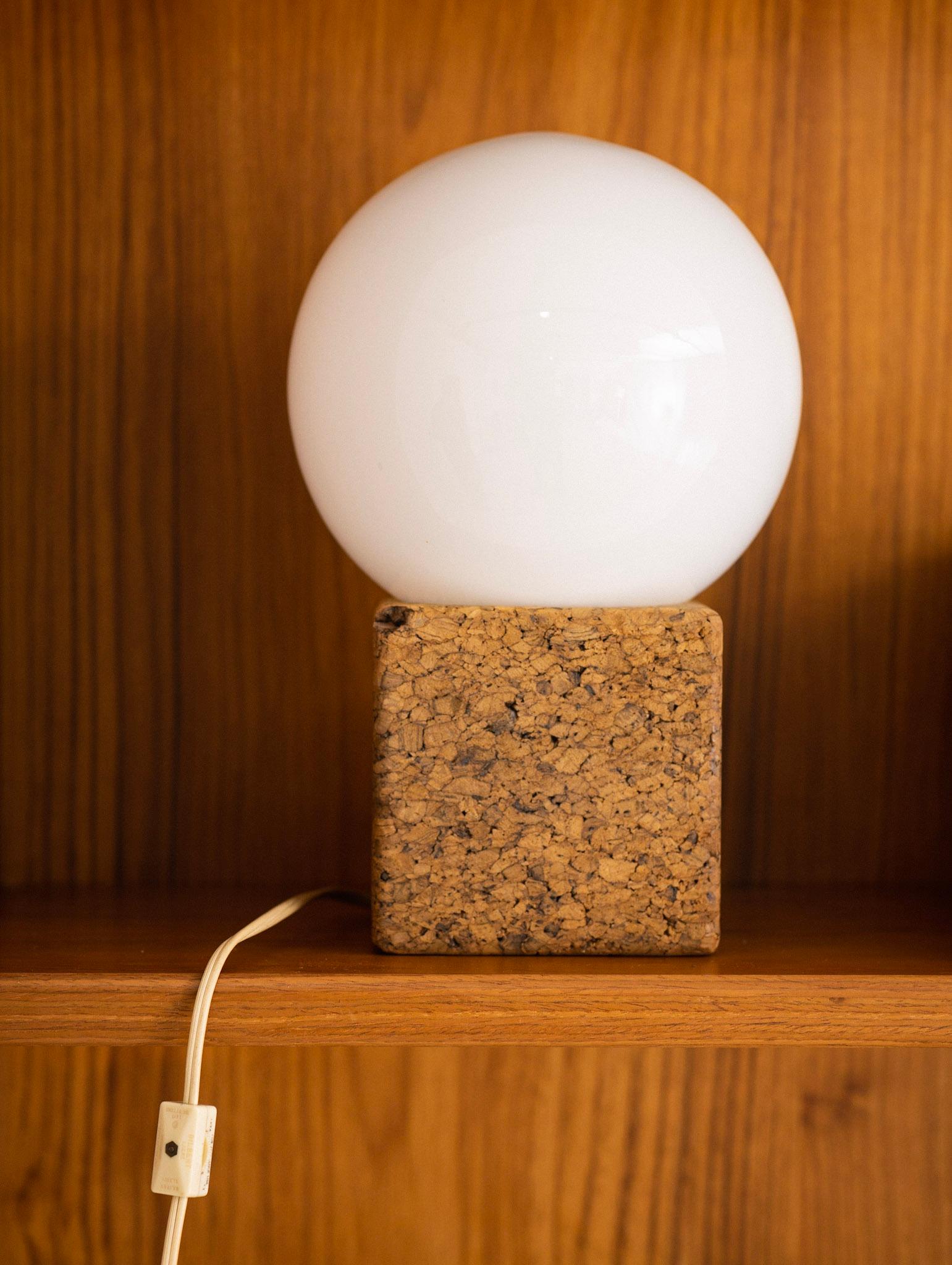 Mid century cork desk lamp with white glass globe. Glass globe simply rests on cork base. Cork base measures 5” x 5” x 5”.