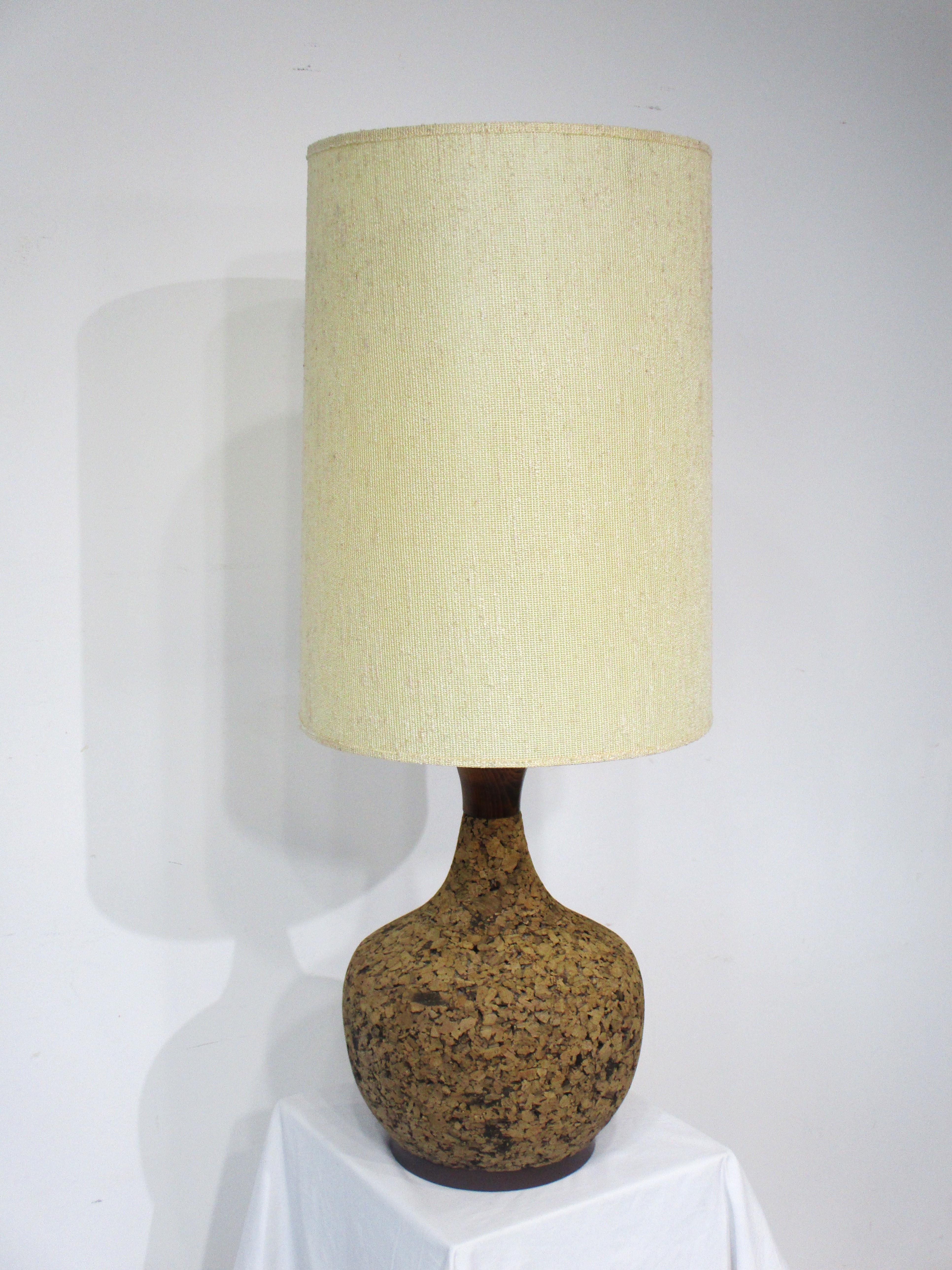 A great return to the past this earthy cork formed table lamp with darker wood top stem and base . The lamp has the original natural linen blended shade and would work with any interior or retro look from the 1960's and 70's .   