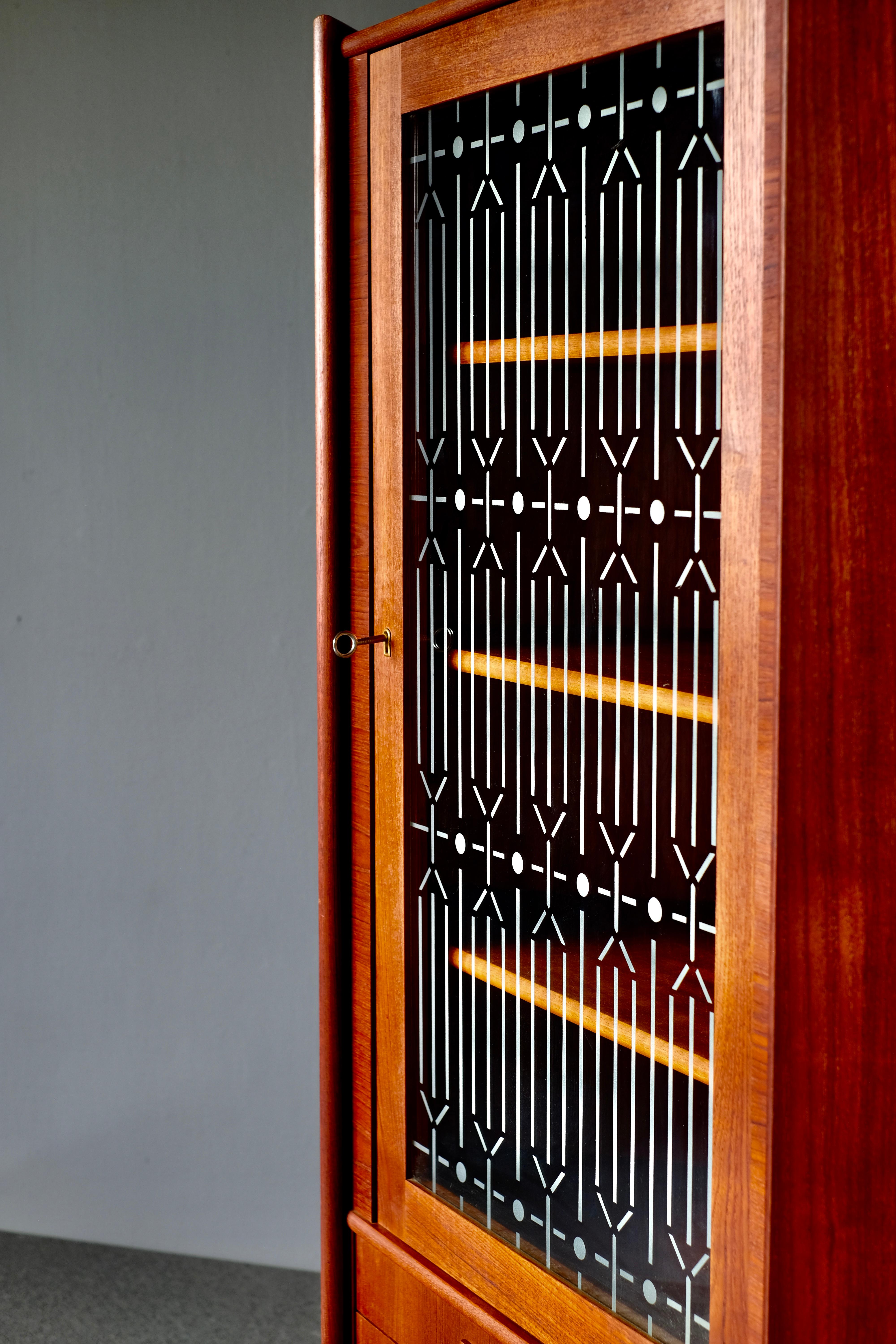 Beautiful corner cupboard in wonderfully patinated teak. It has 2 drawers and a glass door with partially frosted glass housing a storage space with shelves. This lovely piece was produced in the 1960s and is in wonderful condition. The original key