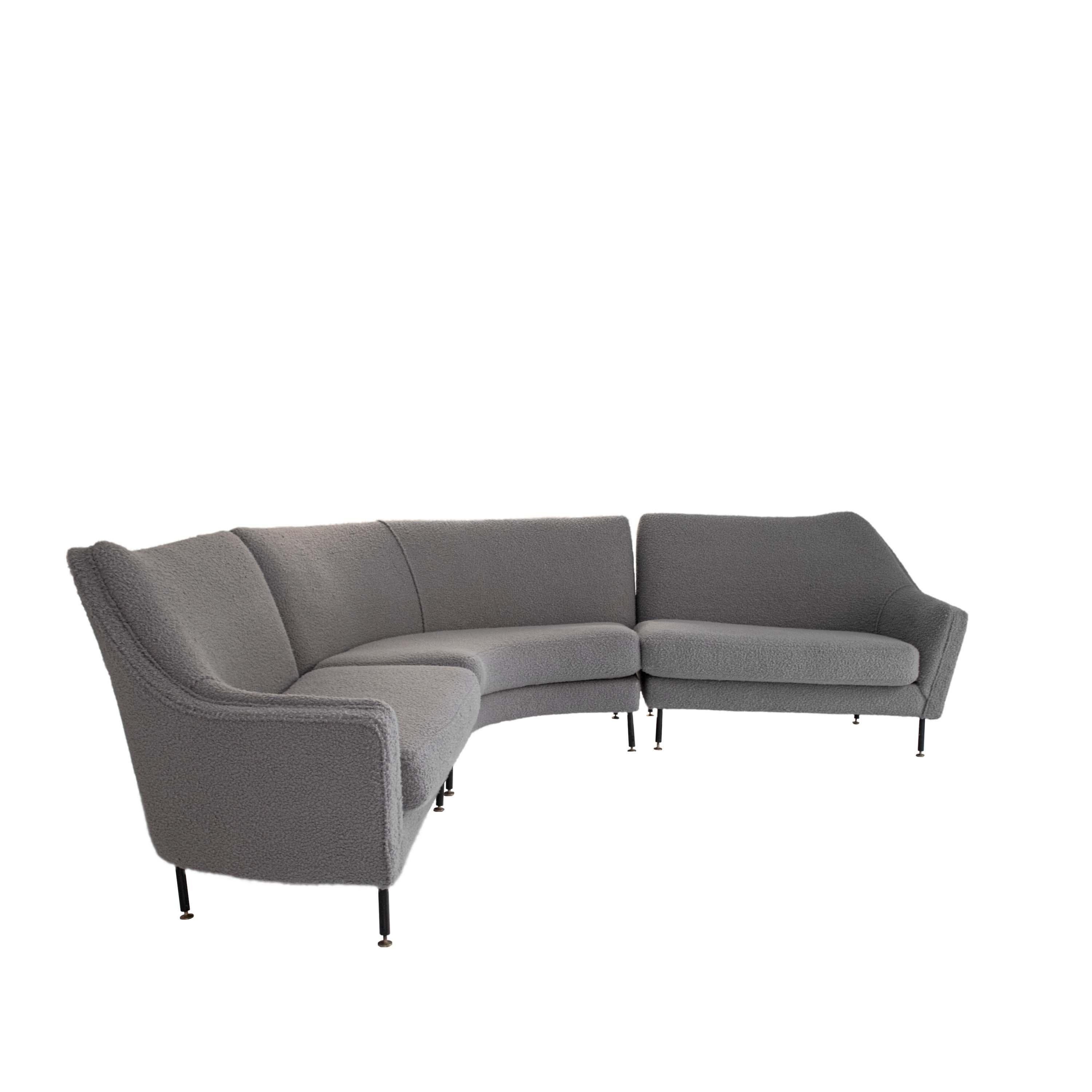 Canapé d'angle composé de trois pièces en bois massif avec une base élastique en métal. Tapissé artisanalement en bouclé de laine gris avec des pieds réglables finis avec des capuchons en laiton. 