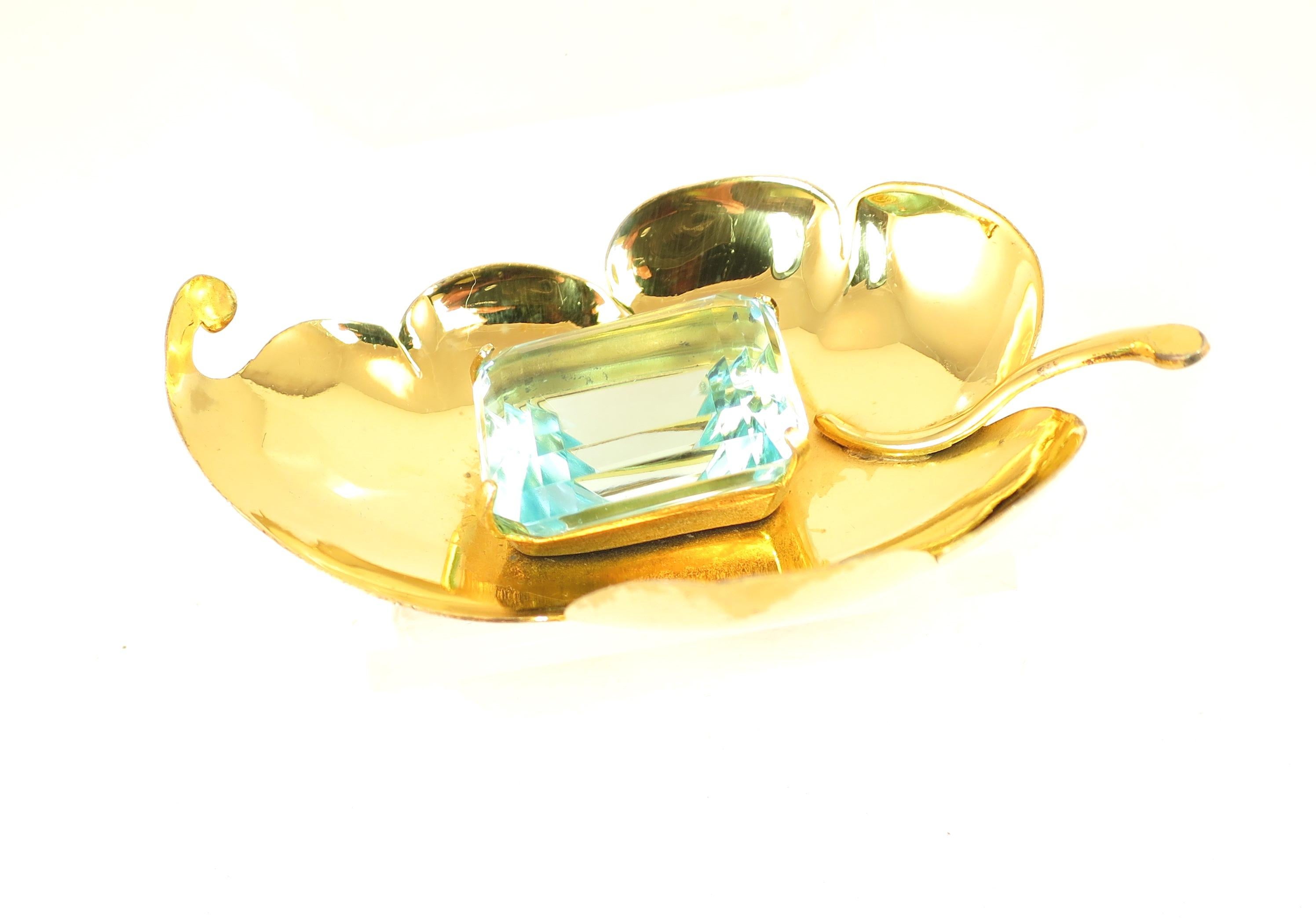 Offered here is a Mid-Century Corocraft gold-plated sterling brooch with a huge faceted aqua glass stone from the 1940s. This is classic and emblematic Corocraft -- hand-cut sterling in a scalloped-edge leaf design, wholly three-dimensional with its