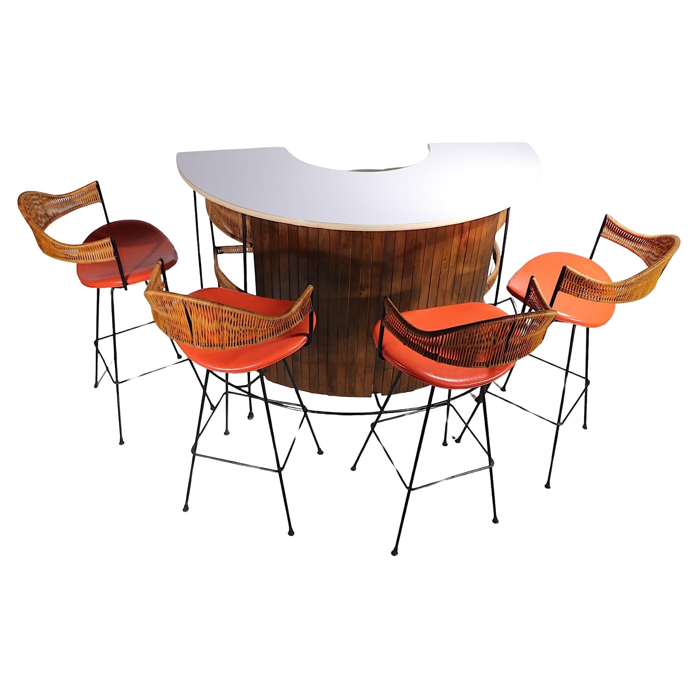 Original 6 pc. bar and stools, designed by Arthur Umanoff, circa 1950/60's. This cool set includes the freestanding curved counter bar, four swivel stools, and the bartenders stool. The bar features a wrought iron frame, white laminate top, a