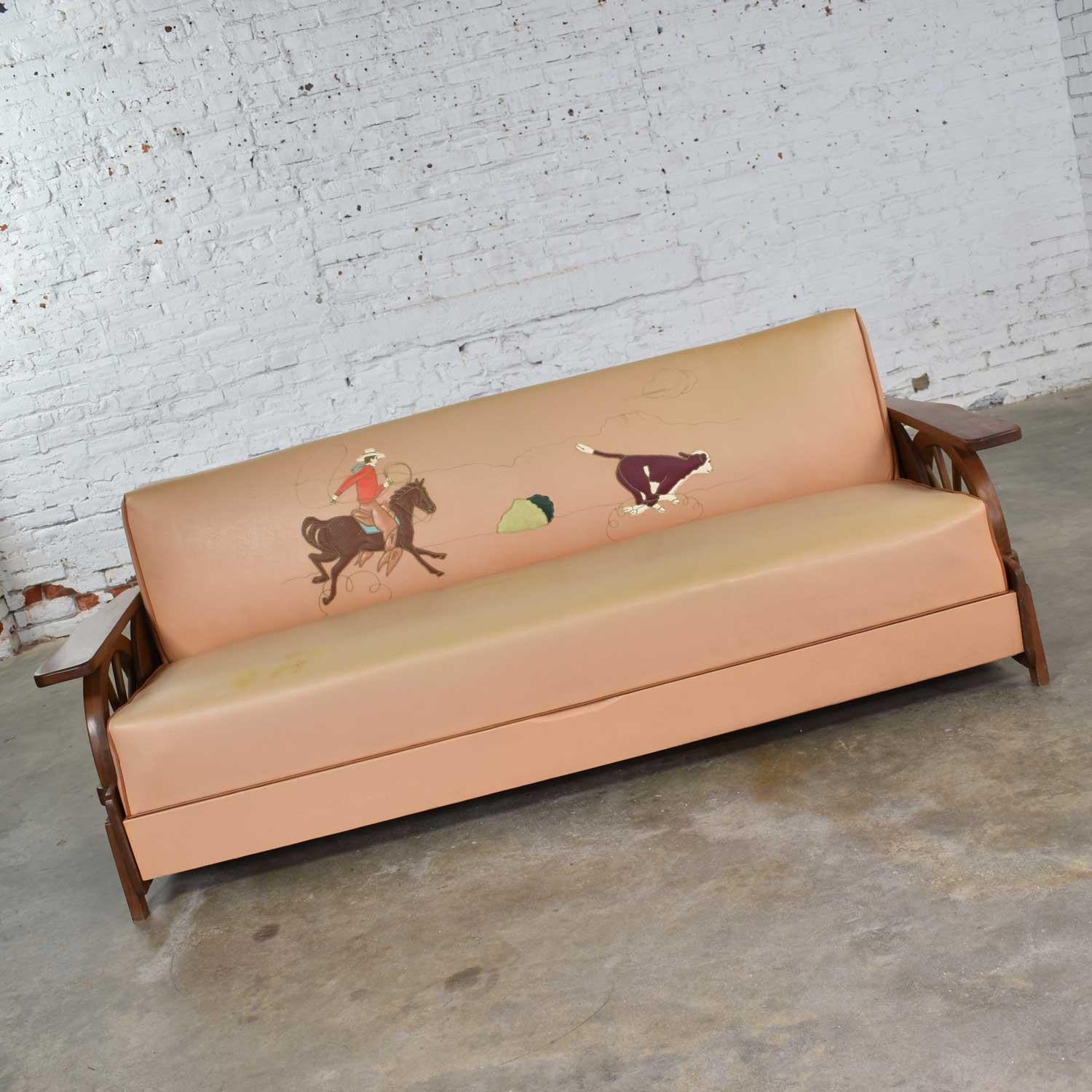 Fabulous midcentury cowboy western wagon wheel convertible sofa reminiscent of a 1950s dude ranch. It is in wonderful vintage condition. There is a small repaired spot in the vinyl of the back, but the cowboy, horse, and steer appliques are in