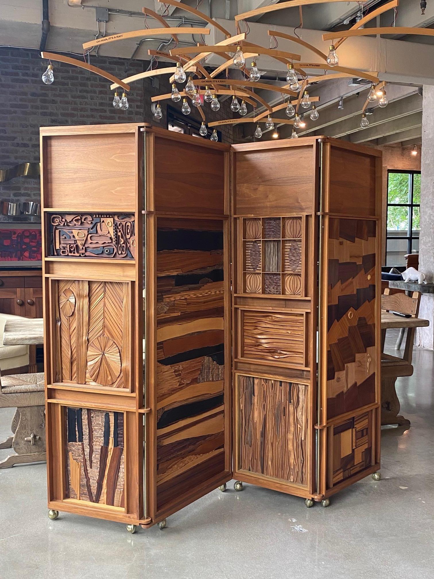 Mid-century modern four panel screen on brass casters.  Unique artisan meets craftsman.  Heavy and well made, the freestanding screen incorporates multiple mixed wood species creating collages which are each framed within the paneled structure. 