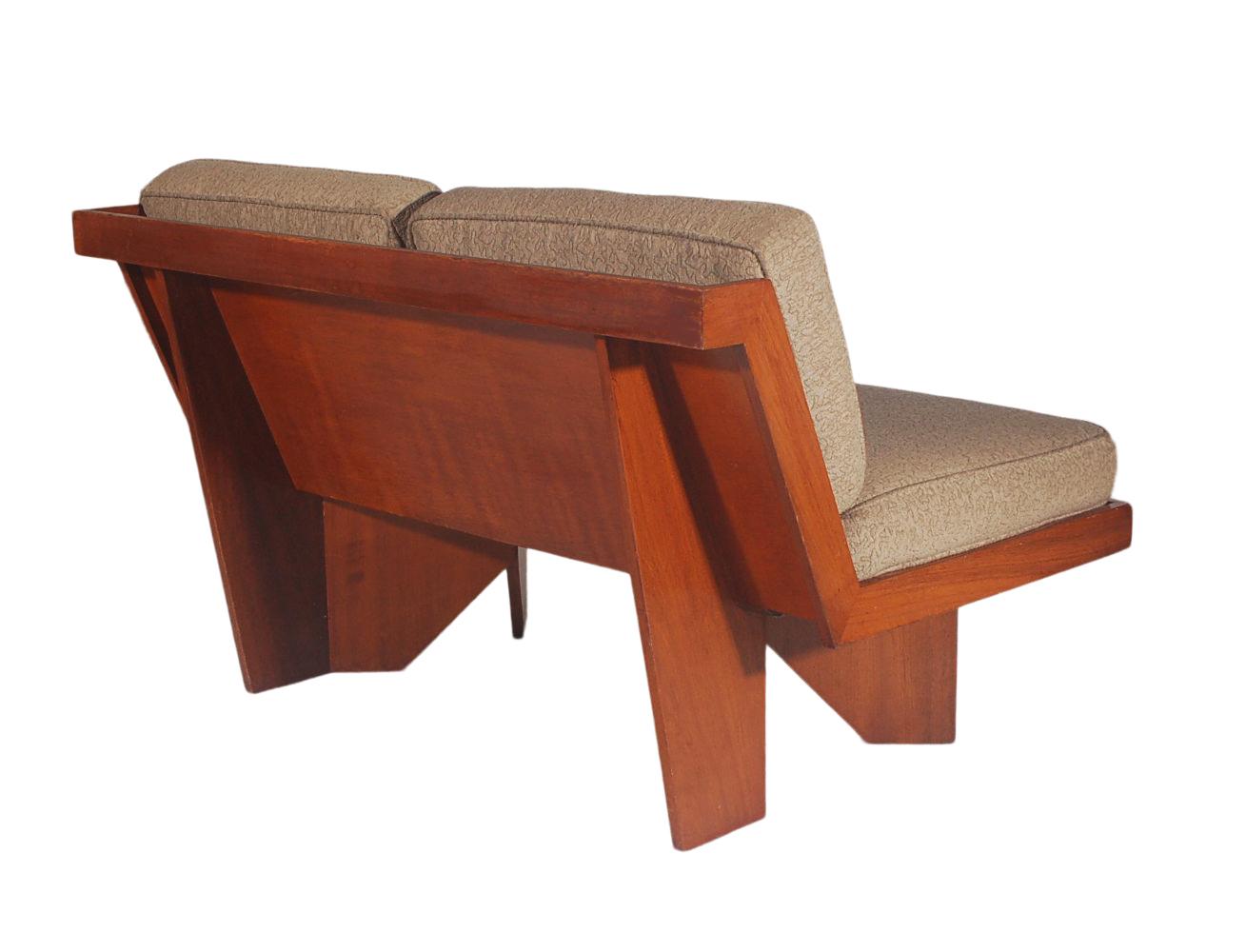 A handsome and well designed loveseat after Frank Lloyd Wright. This is a vintage made piece from the 1940s or 1950s. It features all plywood construction with newer cushions.