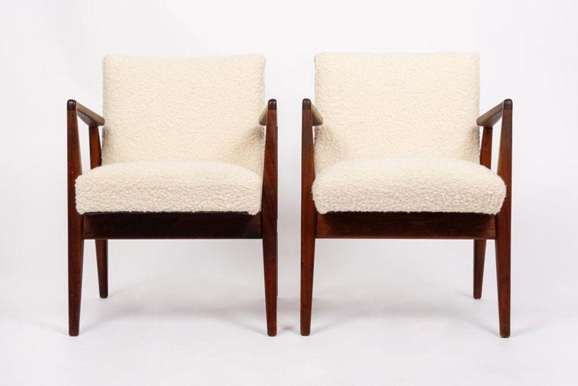 This pair of vintage mid century modern lounge chairs were designed by Jens Risom circa 1960. The classic Danish modern design has clean, minimalist lines and a striking sculptural profile. The lounge chairs feature well-built, solid walnut wood