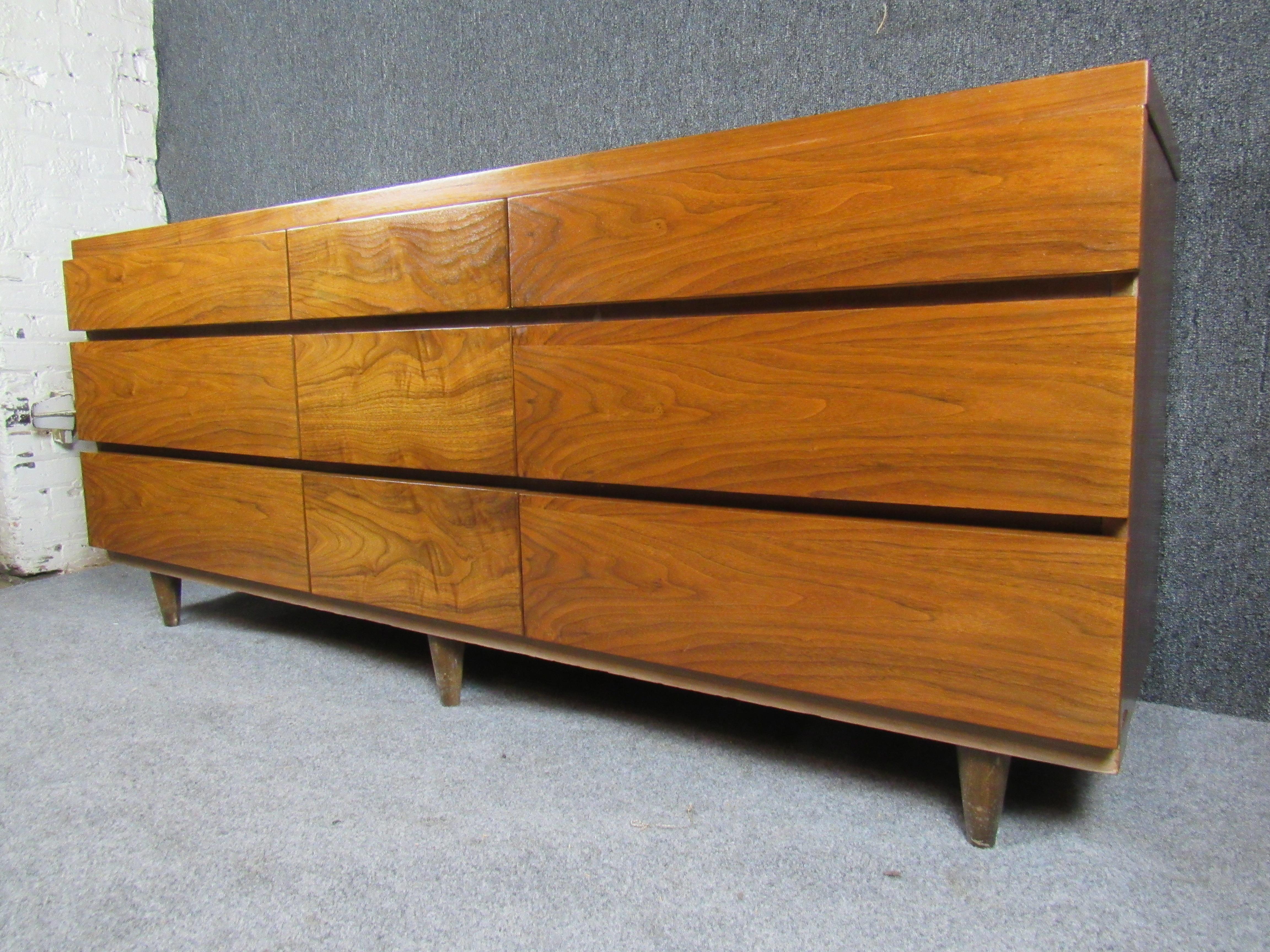 Bring home Classic Mid-Century Modern American minimalism with this gorgeous nine-drawer low dresser from Virginia's Bassett Furniture Industries. Taking aesthetic cues from the timeless designs of Milo Baughman and Merton Gershun, the gorgeous
