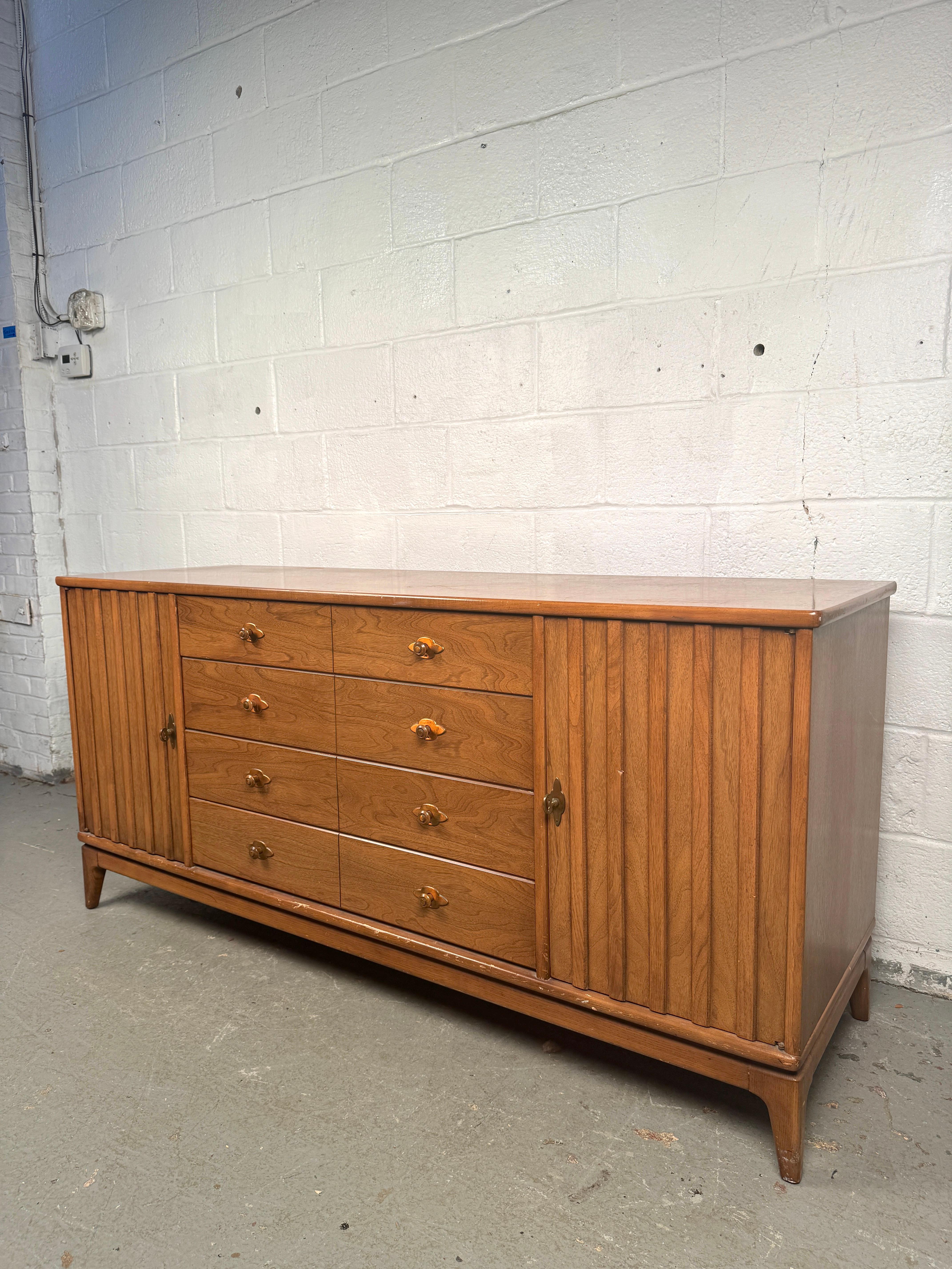 A standout piece from one of America's most iconic mid-century manufacturers, this vintage Broyhill credenza blends timeless design with practical storage. Crafted in beautifully grained wood, the credenza features clean lines, sculpted drawer