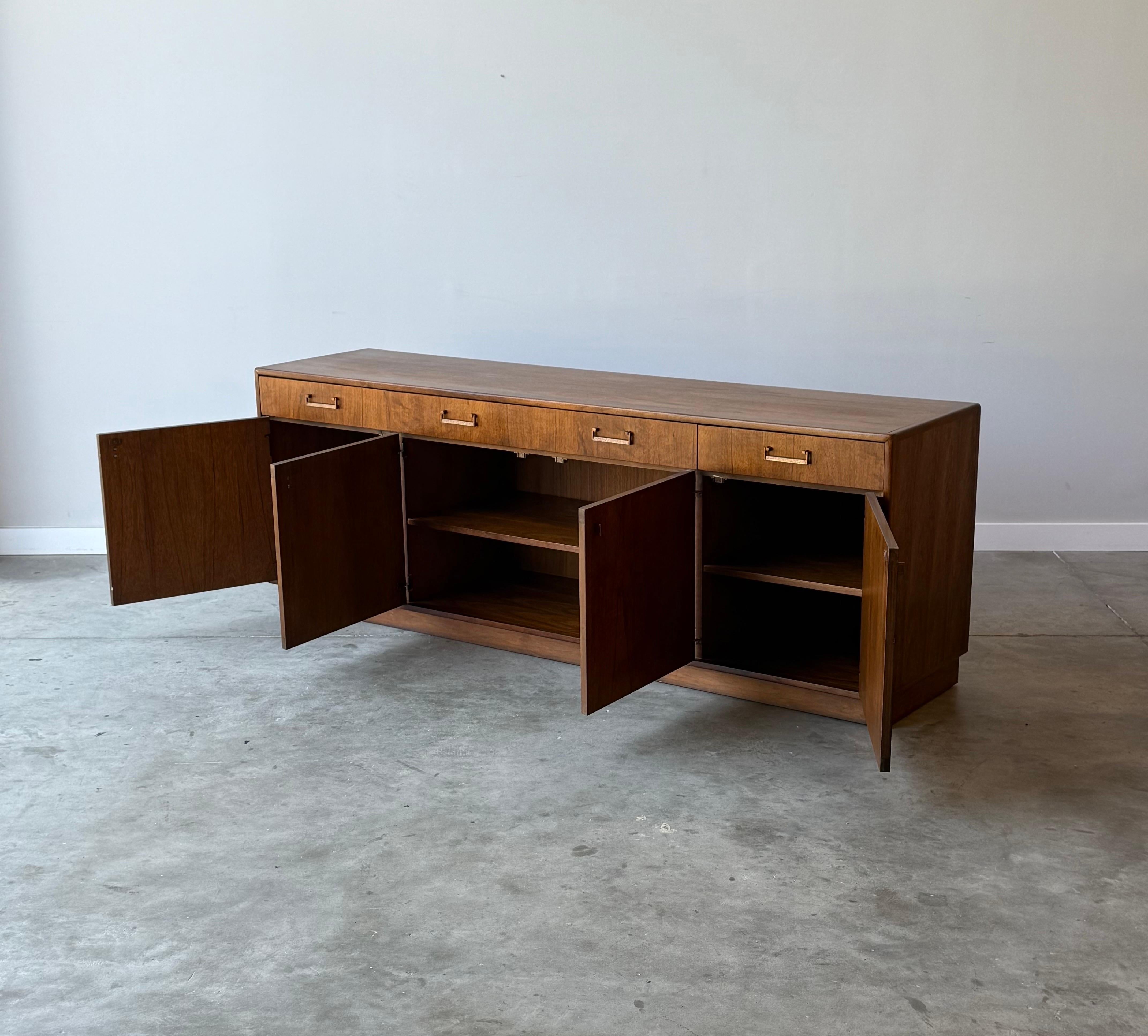 Grande credenza della metà del secolo scorso di Founders, Stati Uniti. Questa credenza in legno presenta venature ricche e vibranti con maniglie in ottone. Con lo stile di Milo Baughman e l'influenza scandinava.

Presenta quattro porte inferiori che