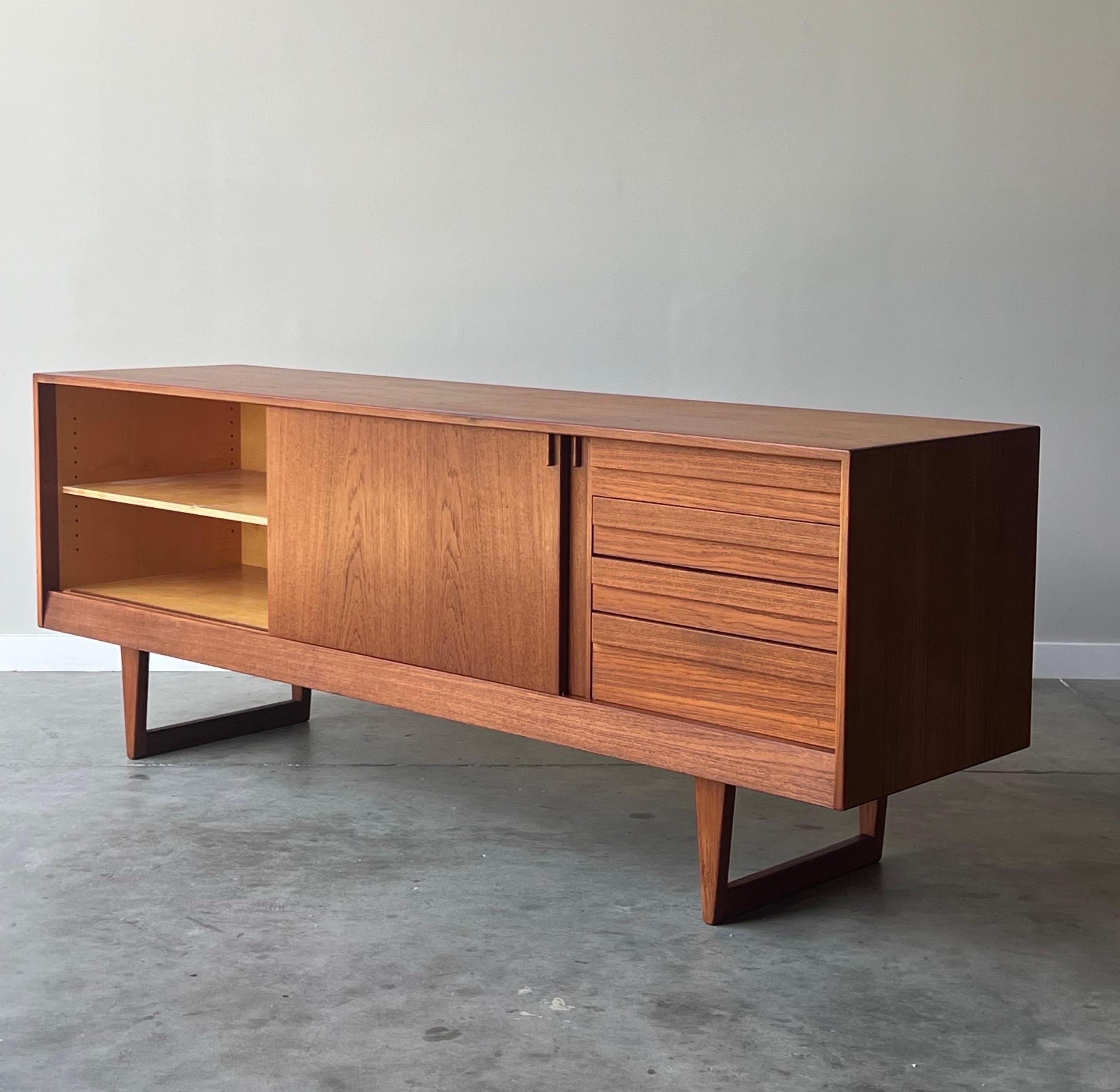 Mid-Century sideboard or credenza by Kurt Østervig for KP Møbler. Made in Denmark circa 1960s from Danish teak wood. Rich warm teak wood and grain throughout. Lots of storage potential.

Two smooth sliding doors open to three shelves of varying