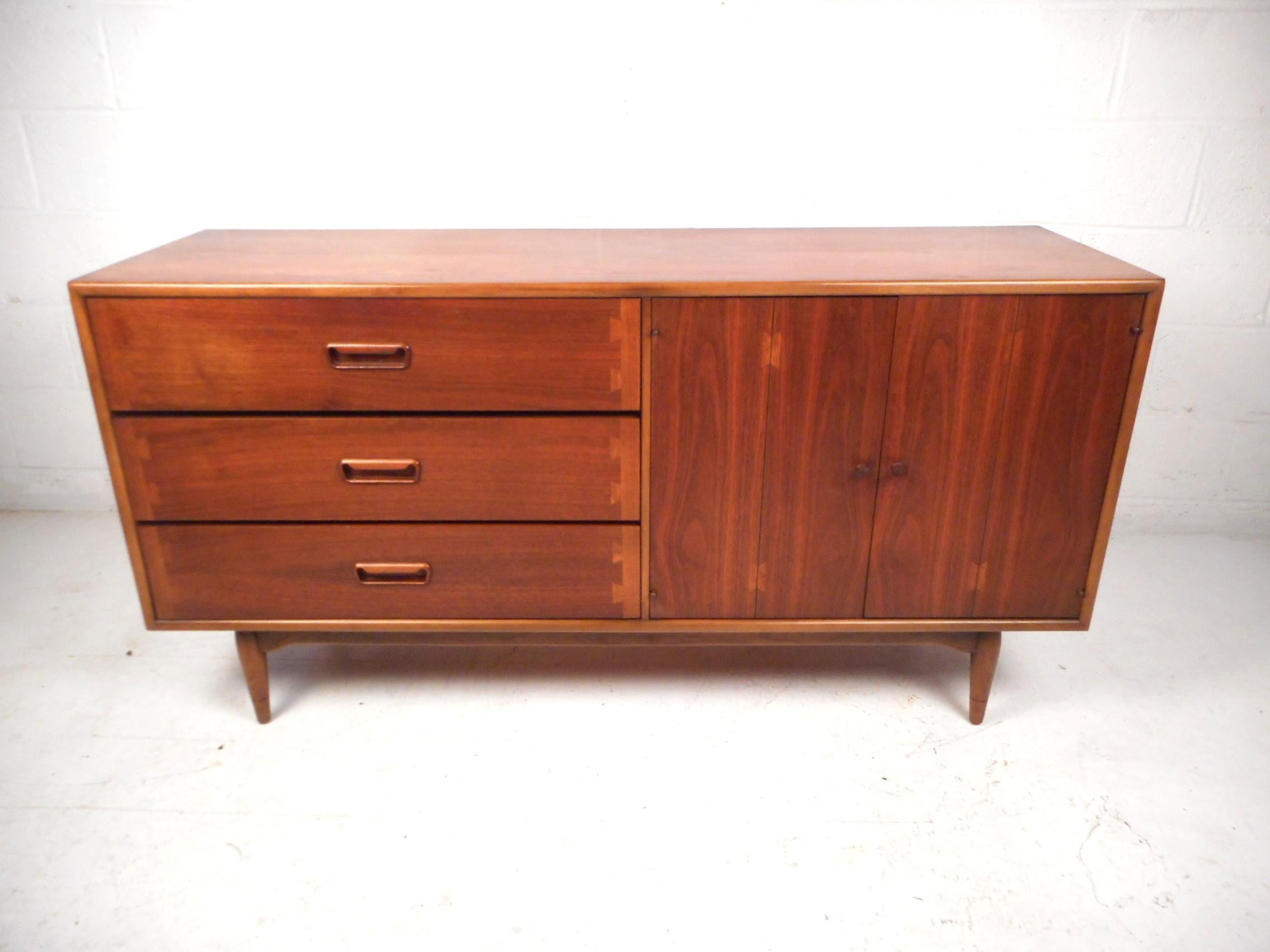 This impressive vintage modern credenza provides storage with style. This credenza boasts a sturdy and well-crafted walnut construction. Three dovetail-jointed drawers and a wide cabinet with one fixed shelf within it provide ample room to