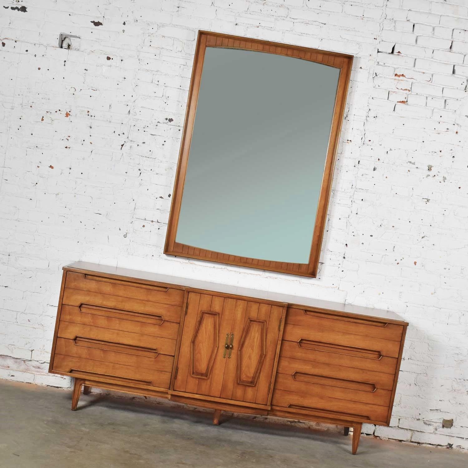 Handsome midcentury credenza or dresser with a large mirror. It is adorned with a hexagon paneled design and brass hardware. It is in wonderful vintage condition. This cabinet has been attributed to Thomasville Omega. The top has been refinished due