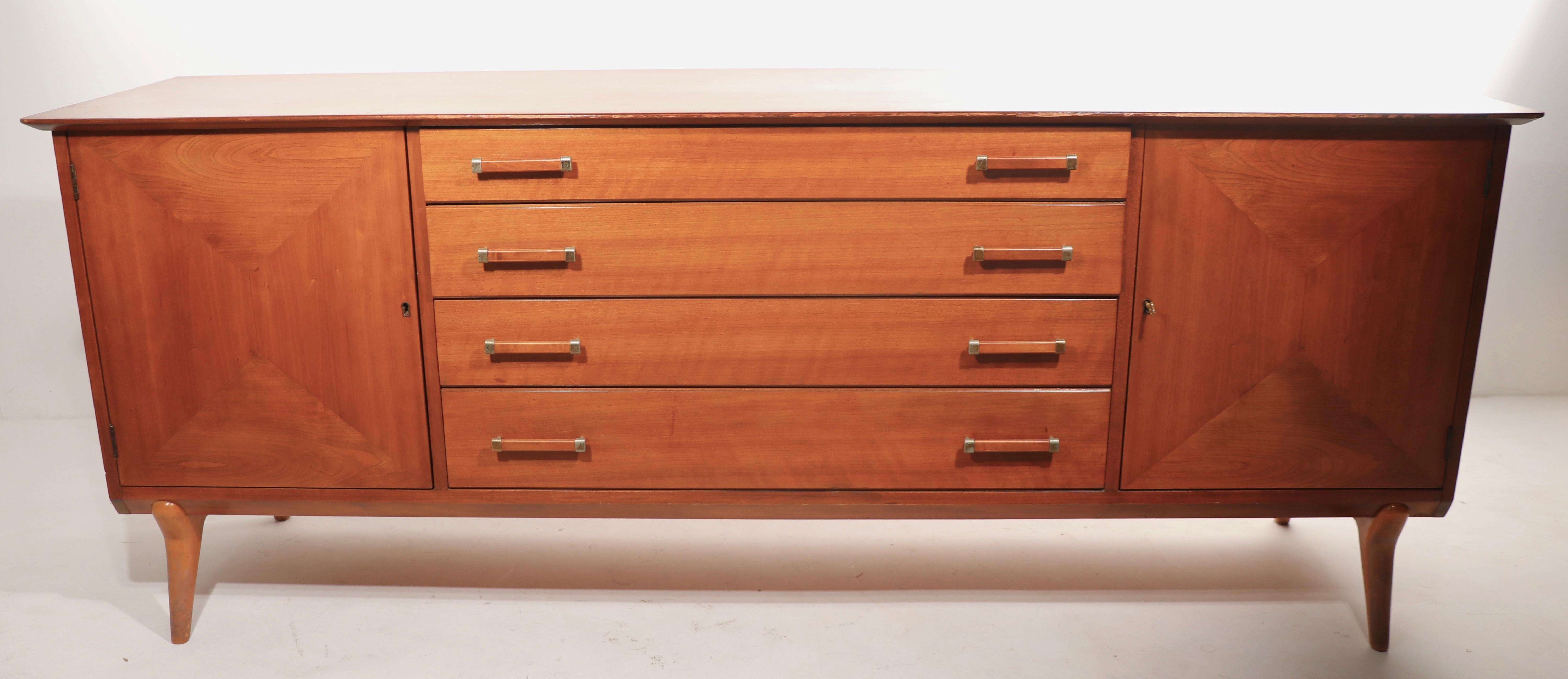 Exceptional Mid-Century Modern server, credenza, server, sideboard designed by Lorenzo Rutili, made by Johnston Furniture Company, retailed by John Stuart. The case has two doors, which swing open to reveal storage space, flanking four center