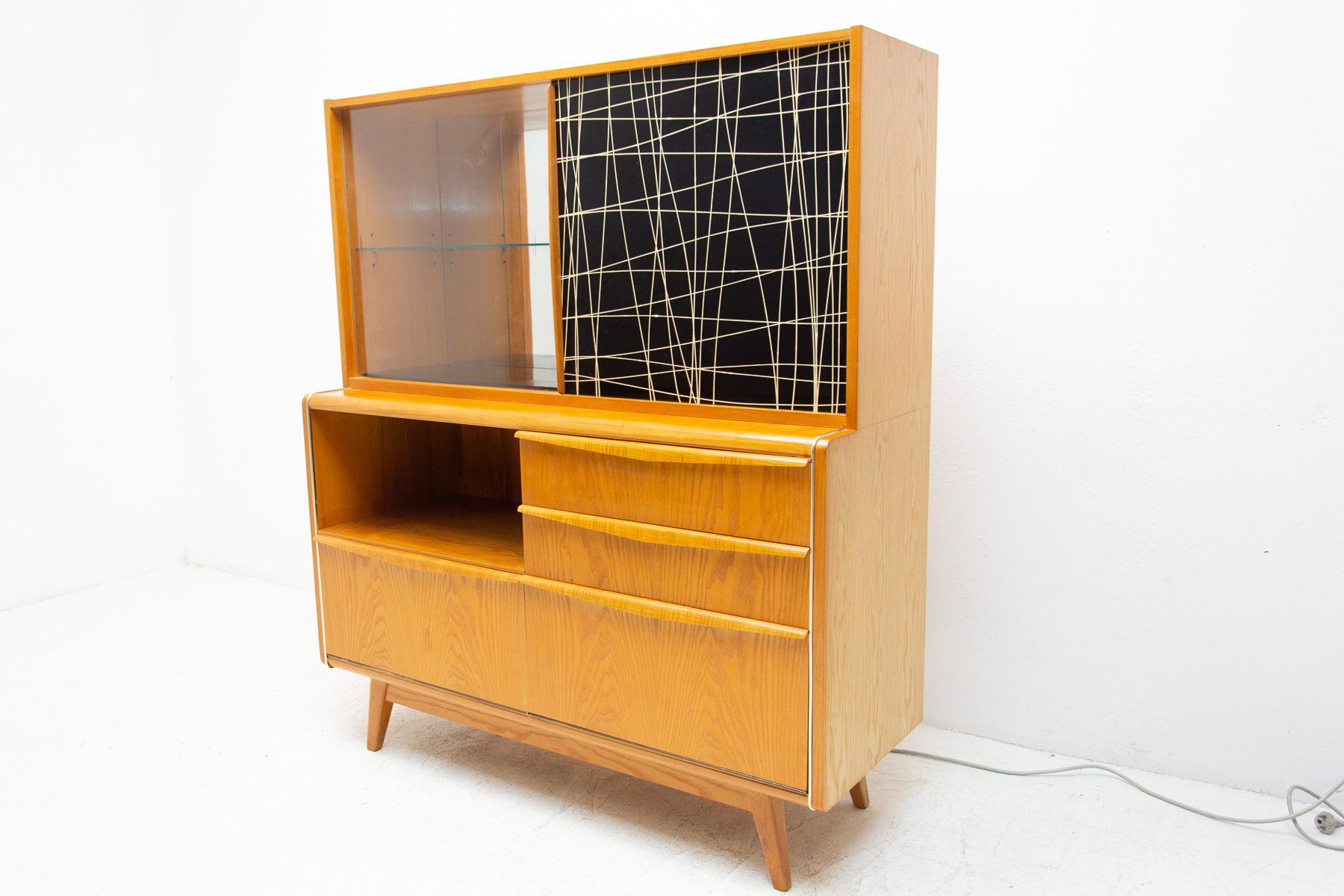 Midcentury credenza/cabinet with bar. It was designed by Hubert Nepožitek & Bohumil Landsman for Jitona company under serial No. U-300 in the 1960´s. It features a glazed upper section with glass shelf to the left and laminated doors to the right,
