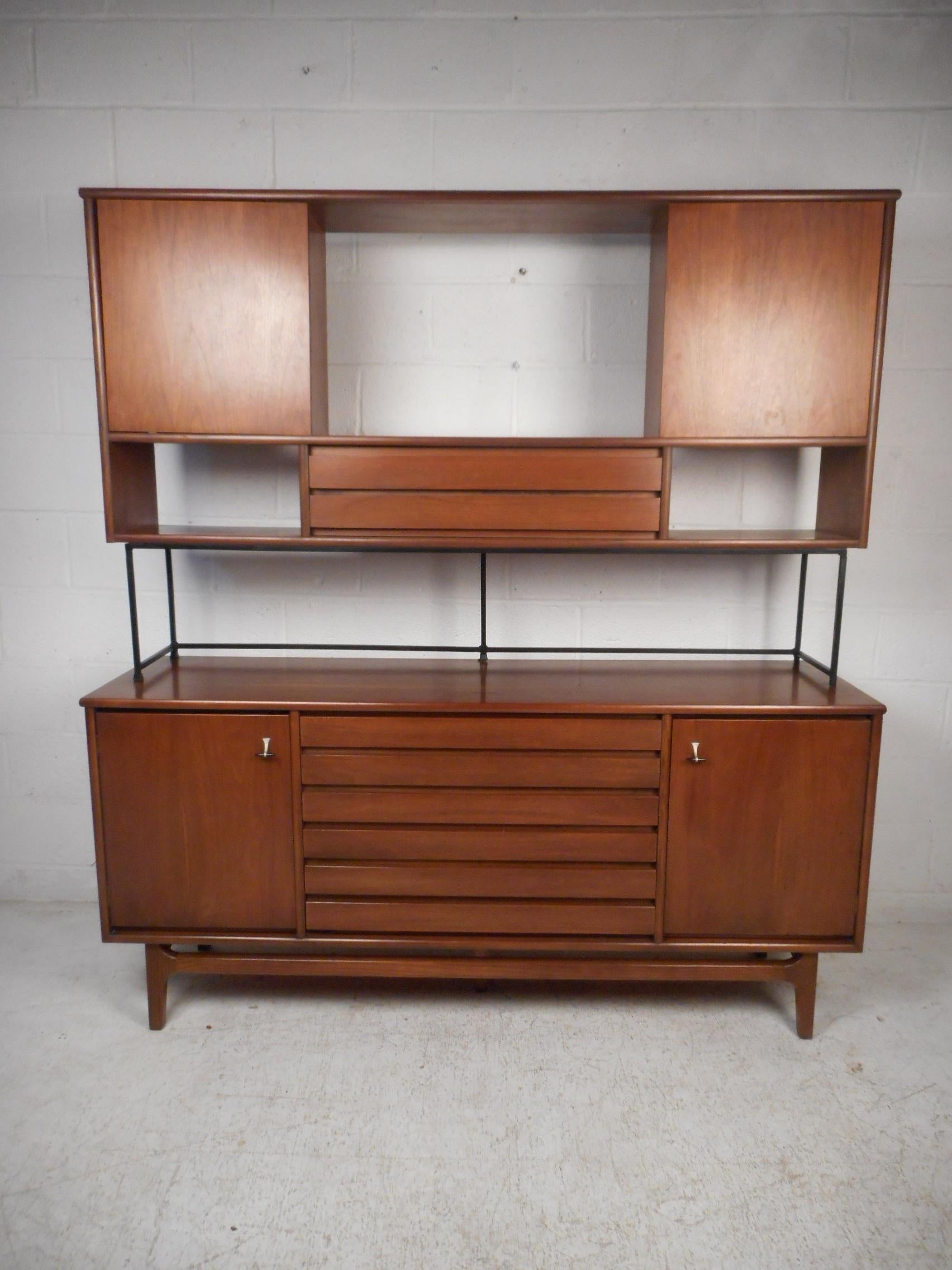 This impressive midcentury piece features a sturady finished walnut construction including a finished back, a credenza with three dovetail jointed drawers with two cabinets on either side provide ample storage space, and a topper piece with sliding