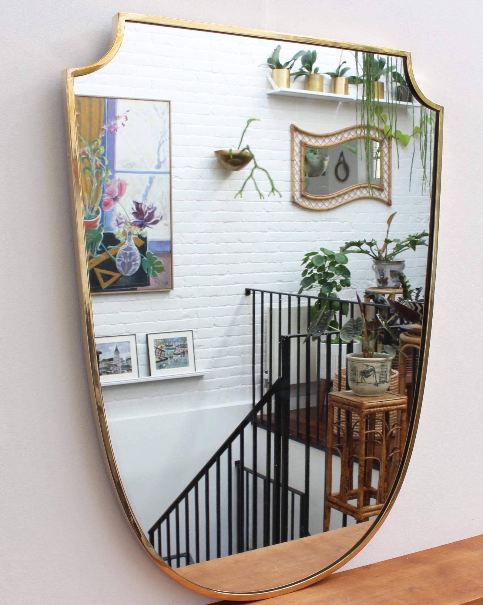 Large midcentury Italian wall mirror with brass frame (circa 1950s). The mirror is crest-shaped - classically elegant and distinct in a modern Gio Ponti style. The piece is in very good vintage condition commensurate with age and usage. A short