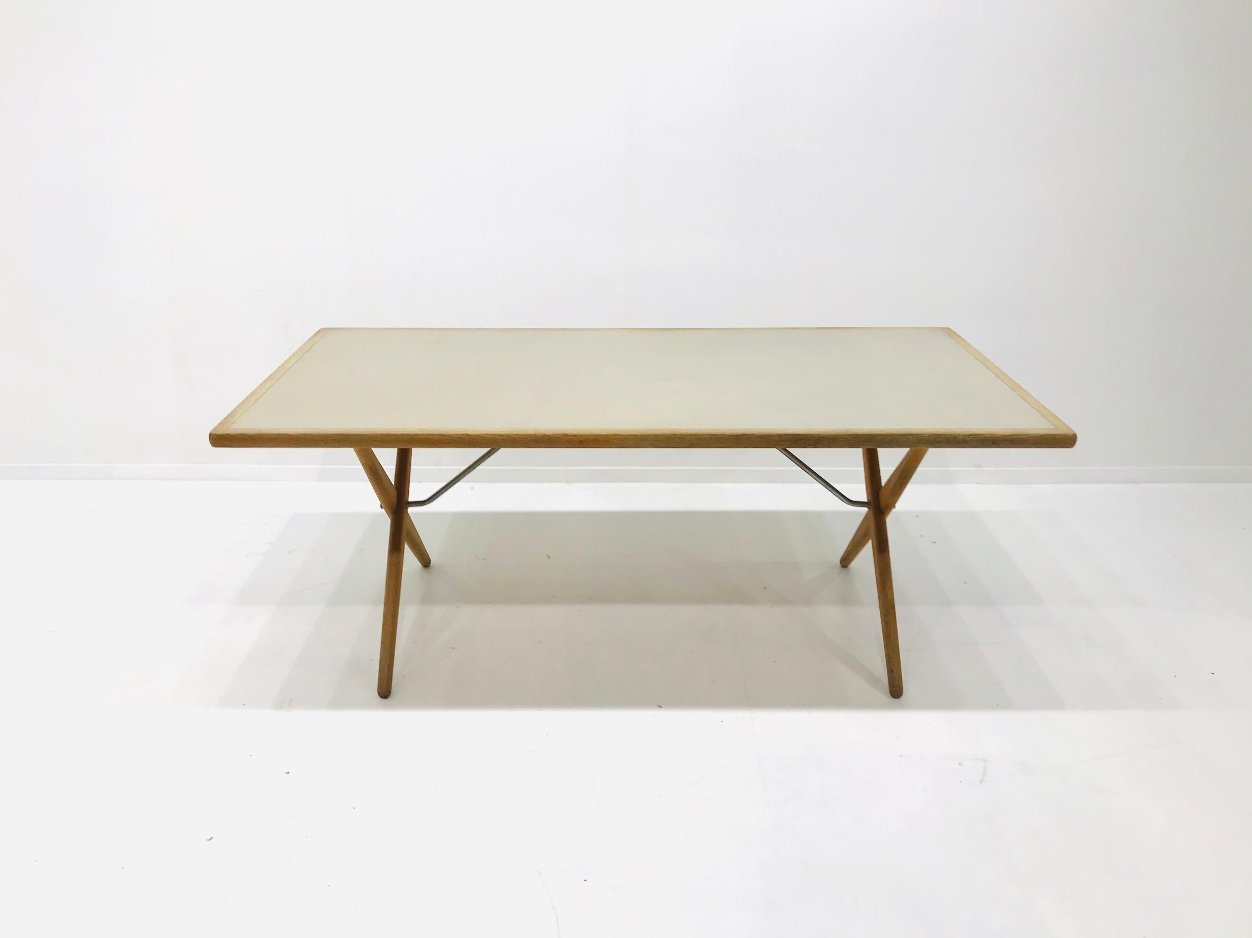 This rare dining table or writingdesk model AT303 was designed by Hans J. Wegner in the 1950s. 
The oak tabletop features a light grey linoleum inlay in very good condition. The tabletop is supported by 2 solid crossed oak legs each connected with