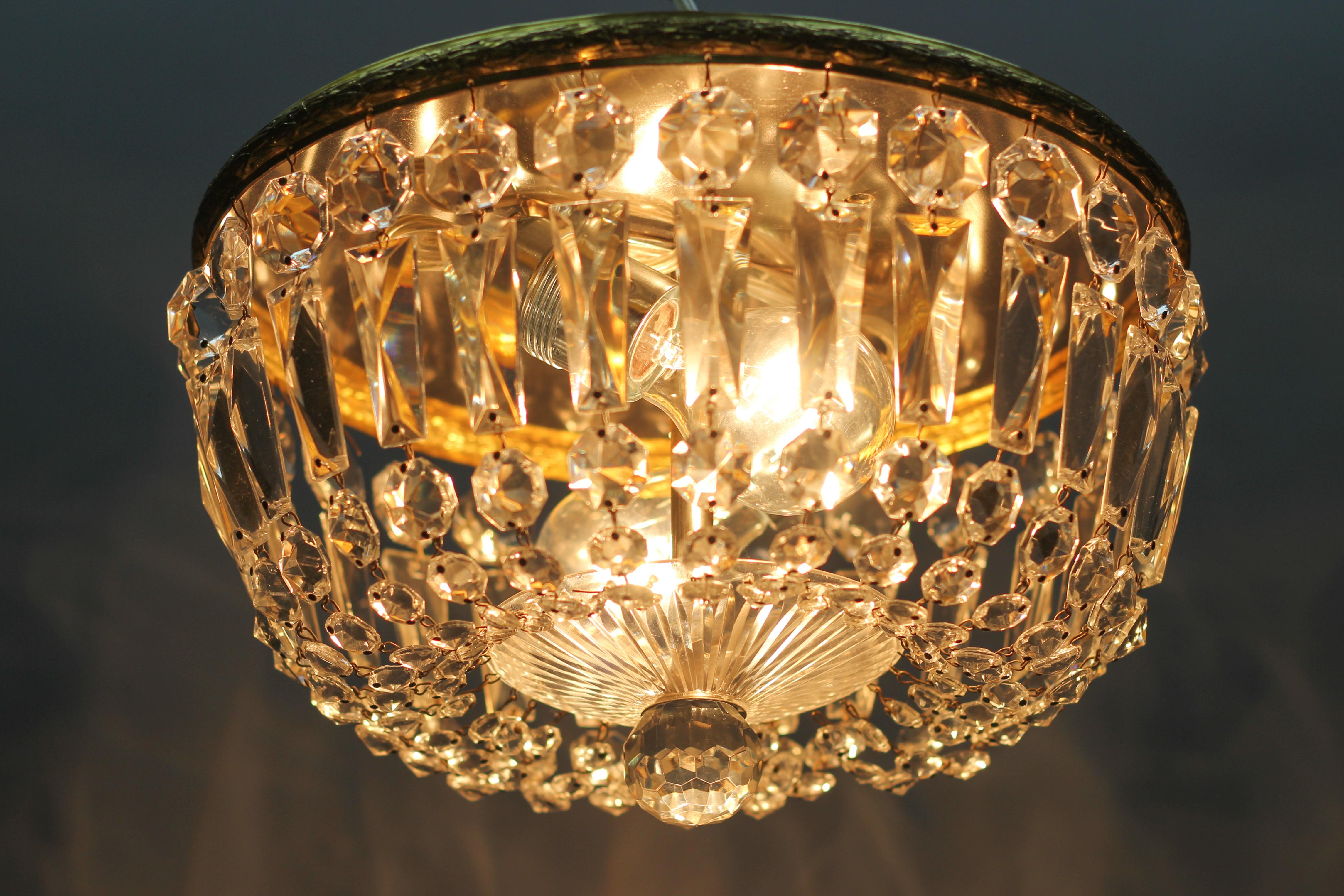 This wonderful ceiling fixture features clear crystal prisms mounted on a brass outer ring and centered with a glass finial.
Two interior lights - two sockets for E27 size light bulbs.
Dimensions: height: 18 cm / 7.08 in; diameter: 31 cm / 12.2 in.