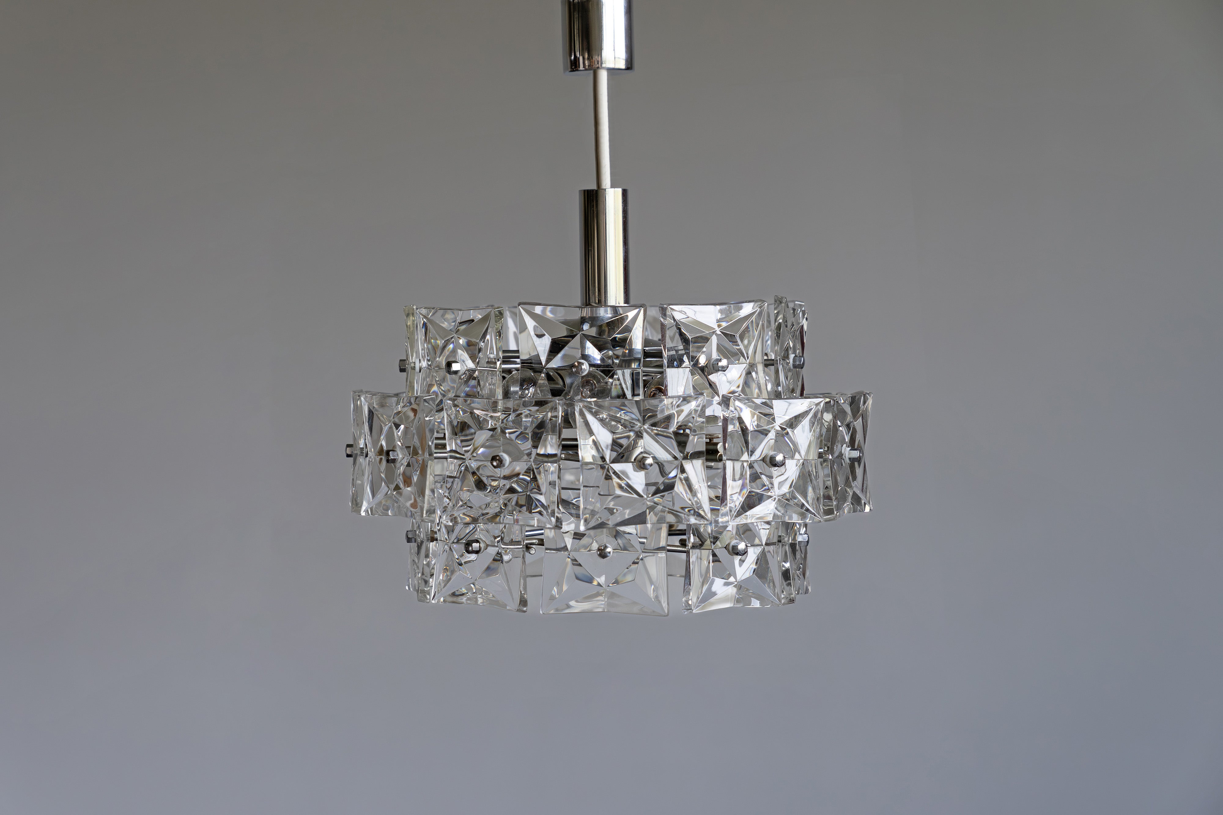 Kronleuchter von Kinkeldey aus verchromtem Stahl und Kristallglas. Mit ihren zwölf E14-Fassungen sorgt sie für ausreichend gleichmäßiges Licht.